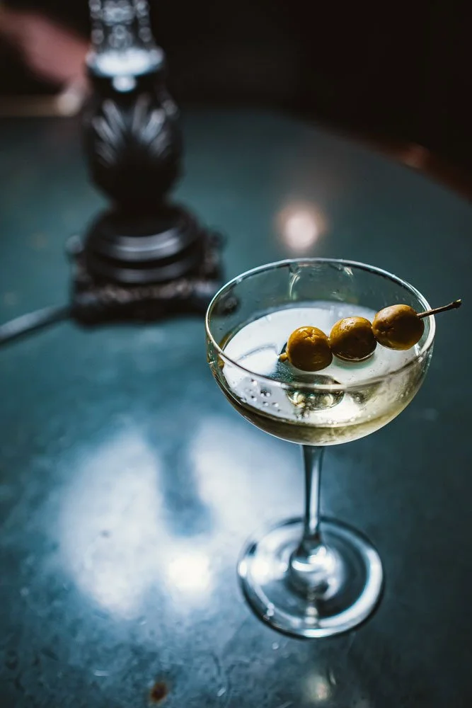 A martini with three olives in a coupe glass