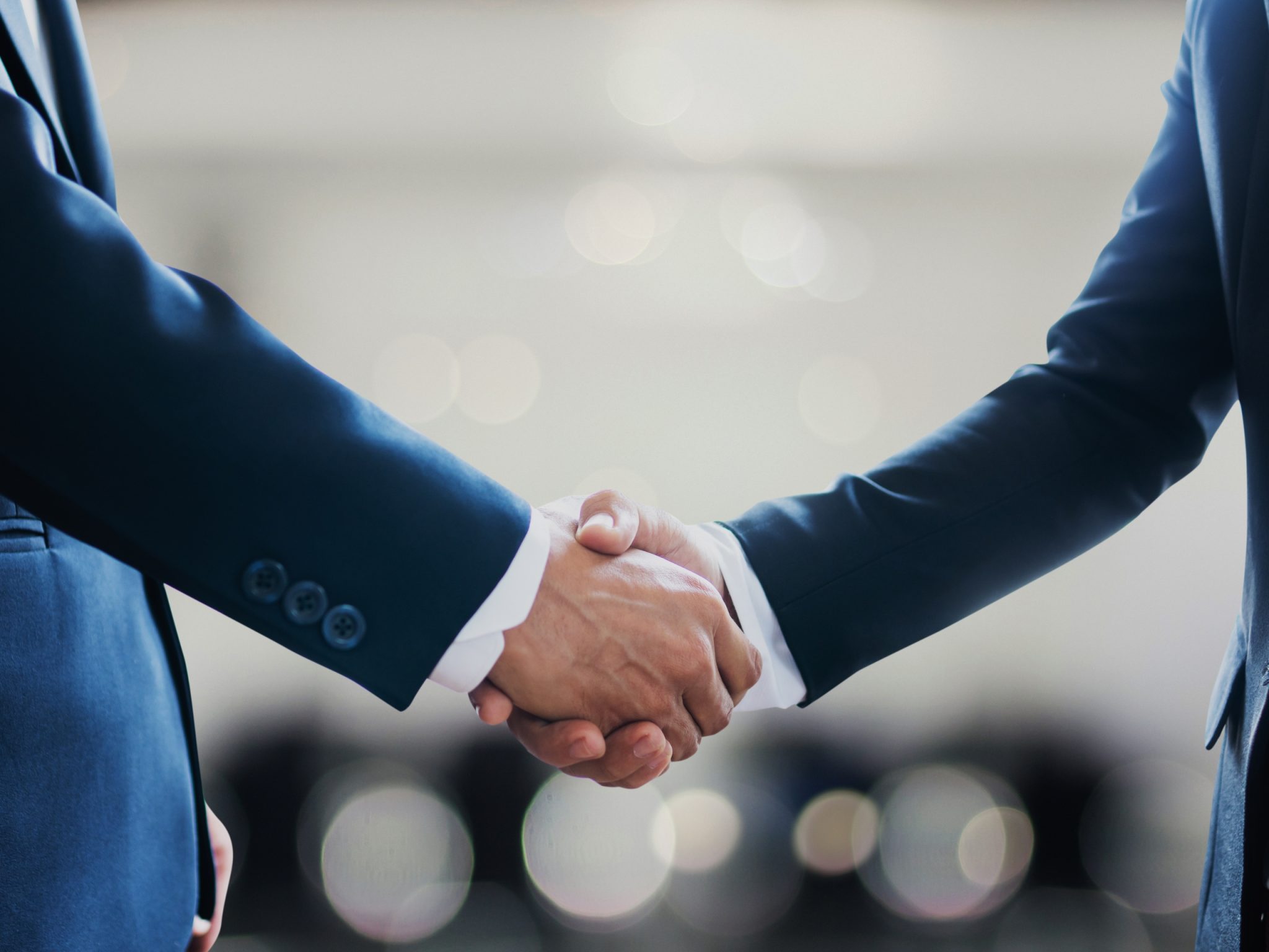 Two men in dark business suits shaking hands