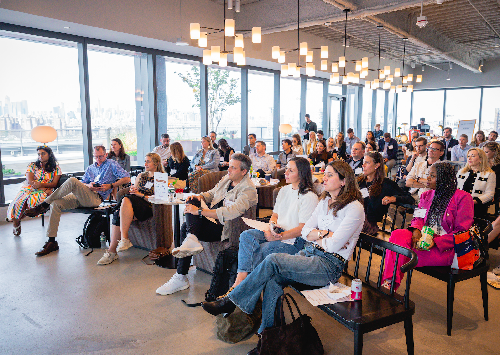 Large group of executives seated in rows at a bright, skyline-view venue