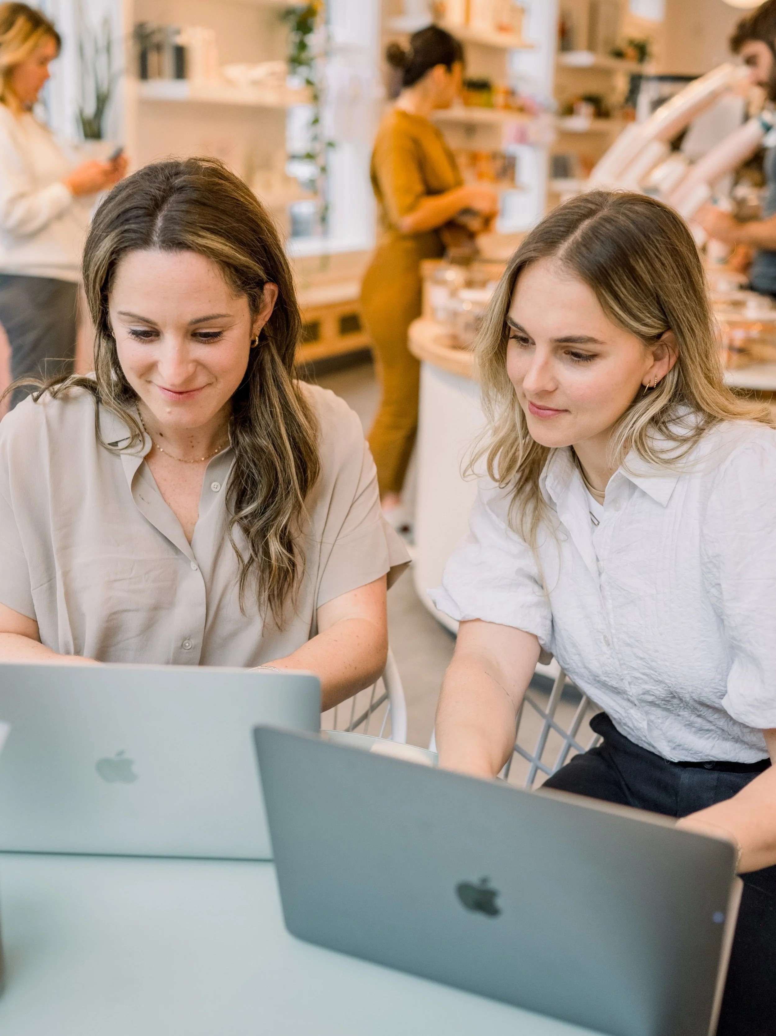 Rachel Naar and a colleague working side by side over laptops in a bright café space