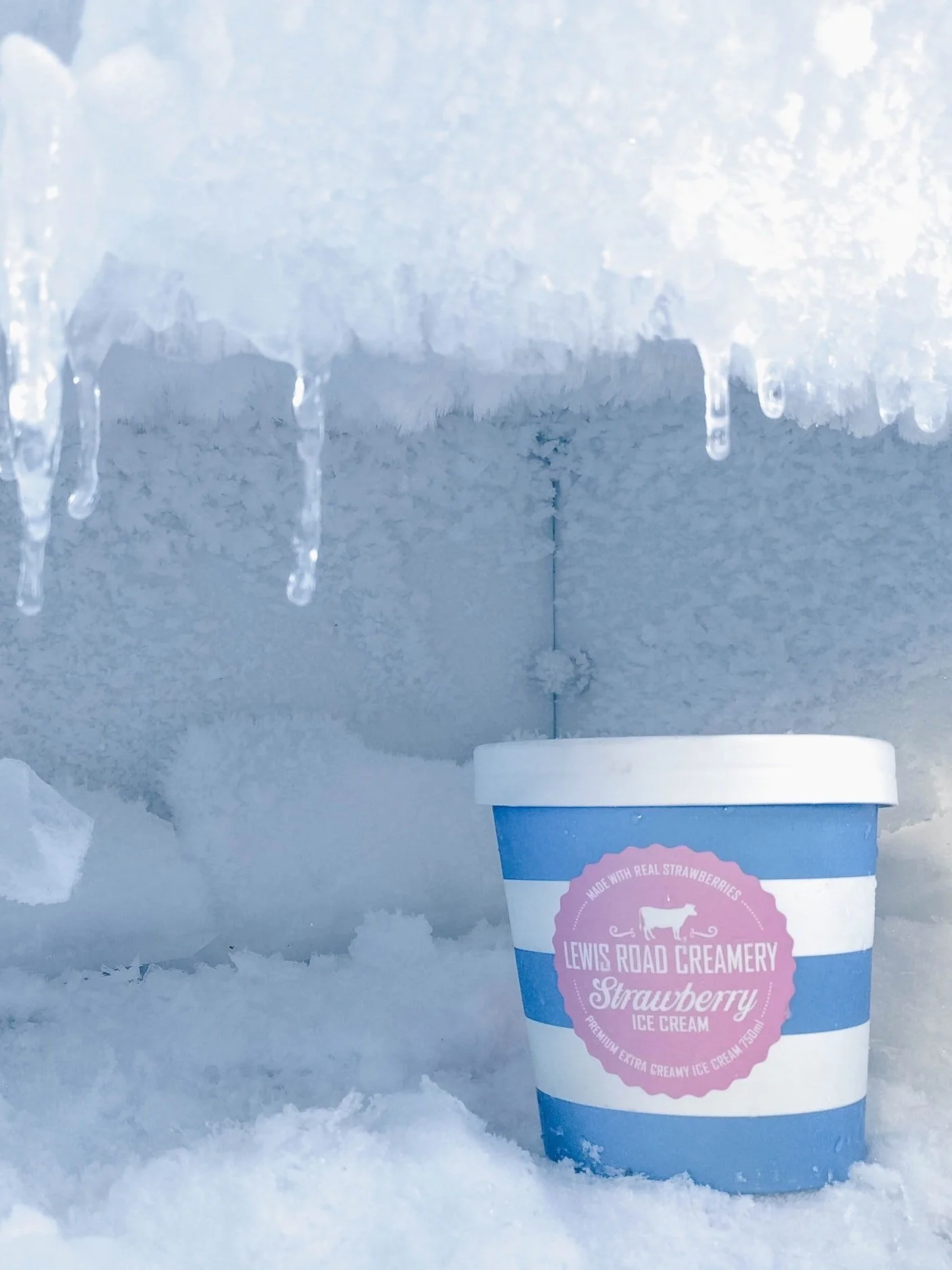 A pint of strawberry ice cream sitting in snow