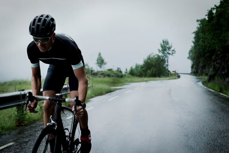 Road cyclist riding a wet rural road in overcast weather