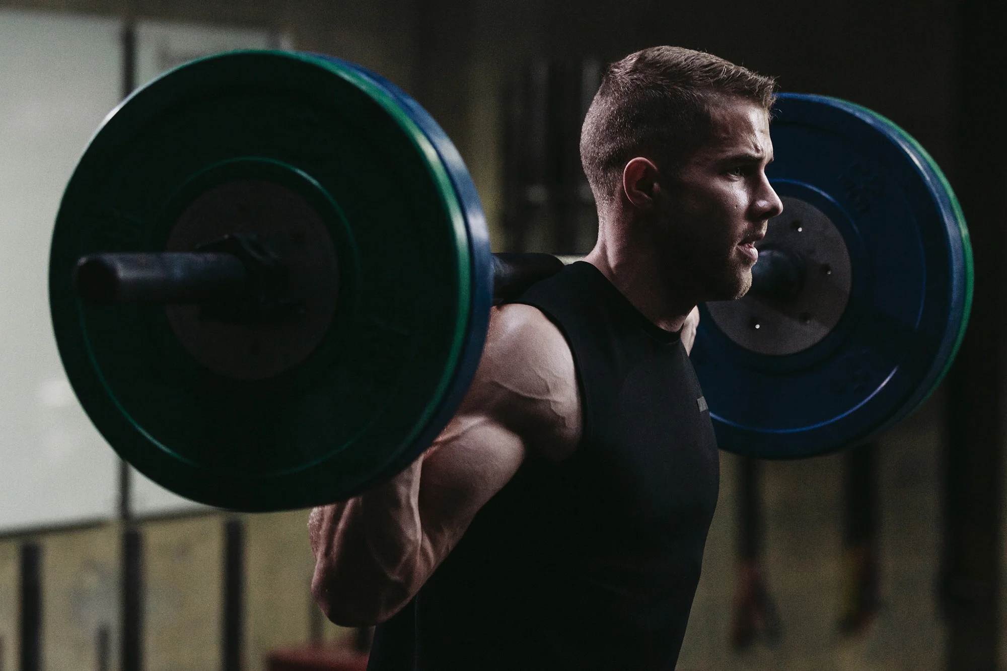 Athlete performing a barbell back squat in a dark gym