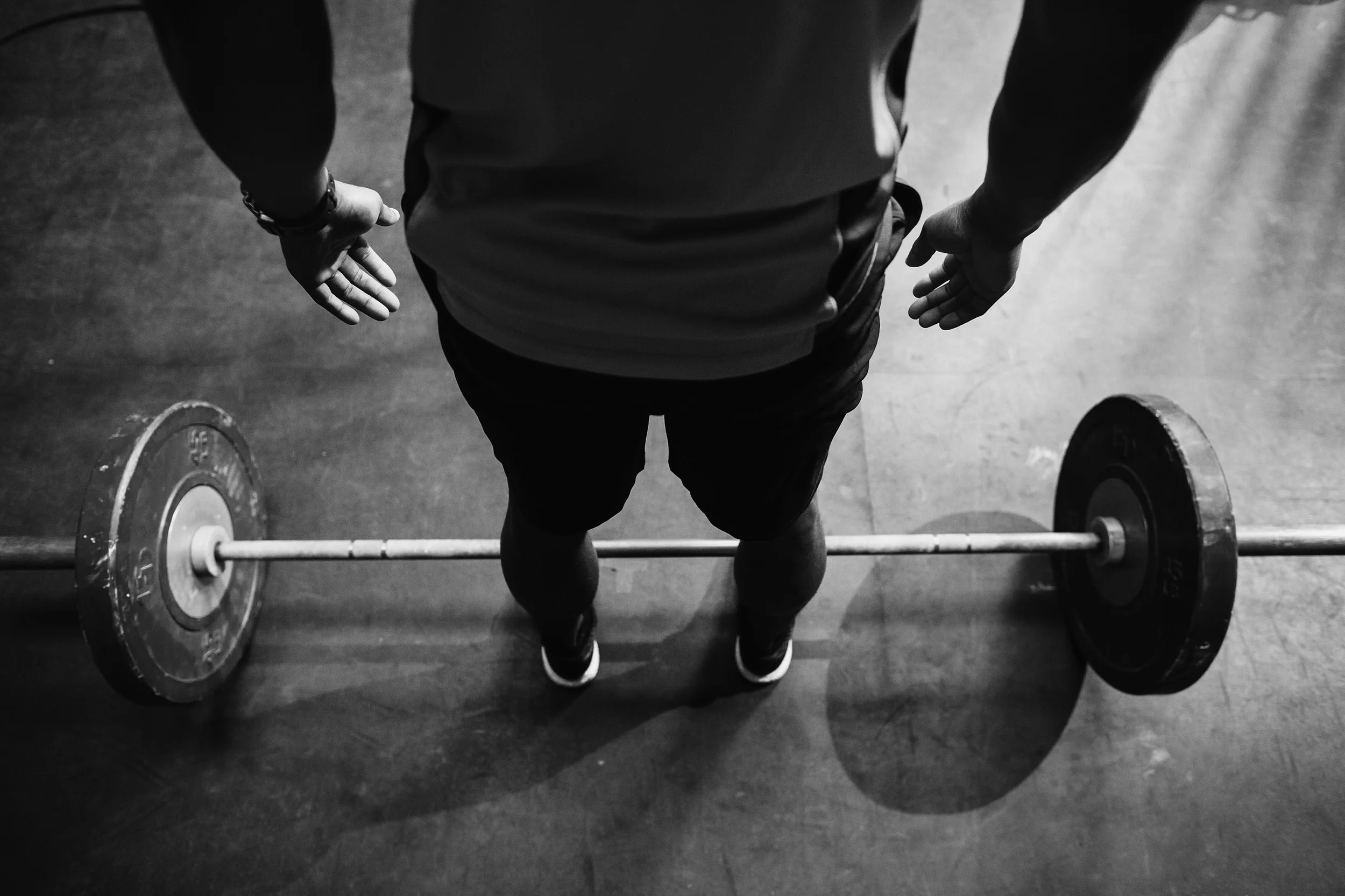Black and white overhead view of an athlete standing over a loaded barbell before a deadlift