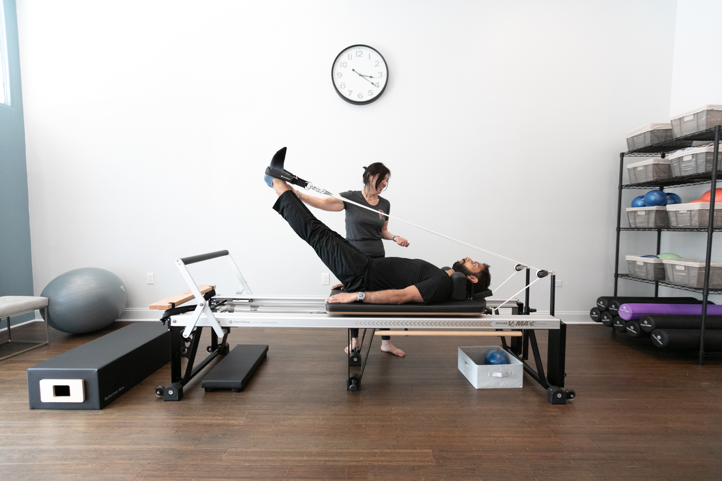 Female instructor guiding a client on a Pilates reformer