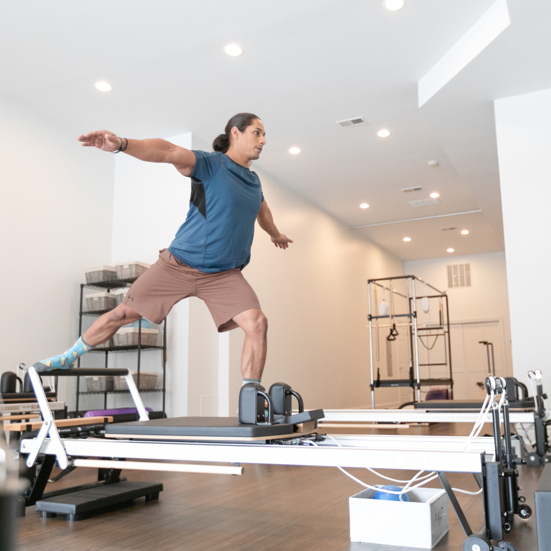 Man balancing on one leg on top of a Pilates reformer