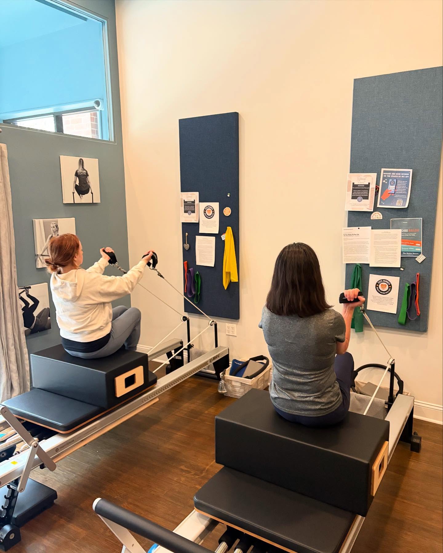 Two clients doing a rowing exercise on Pilates reformers