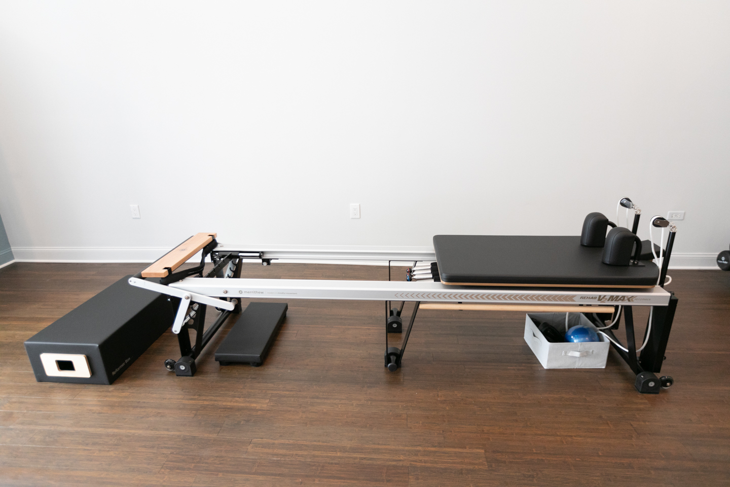 A single Pilates reformer against a white wall