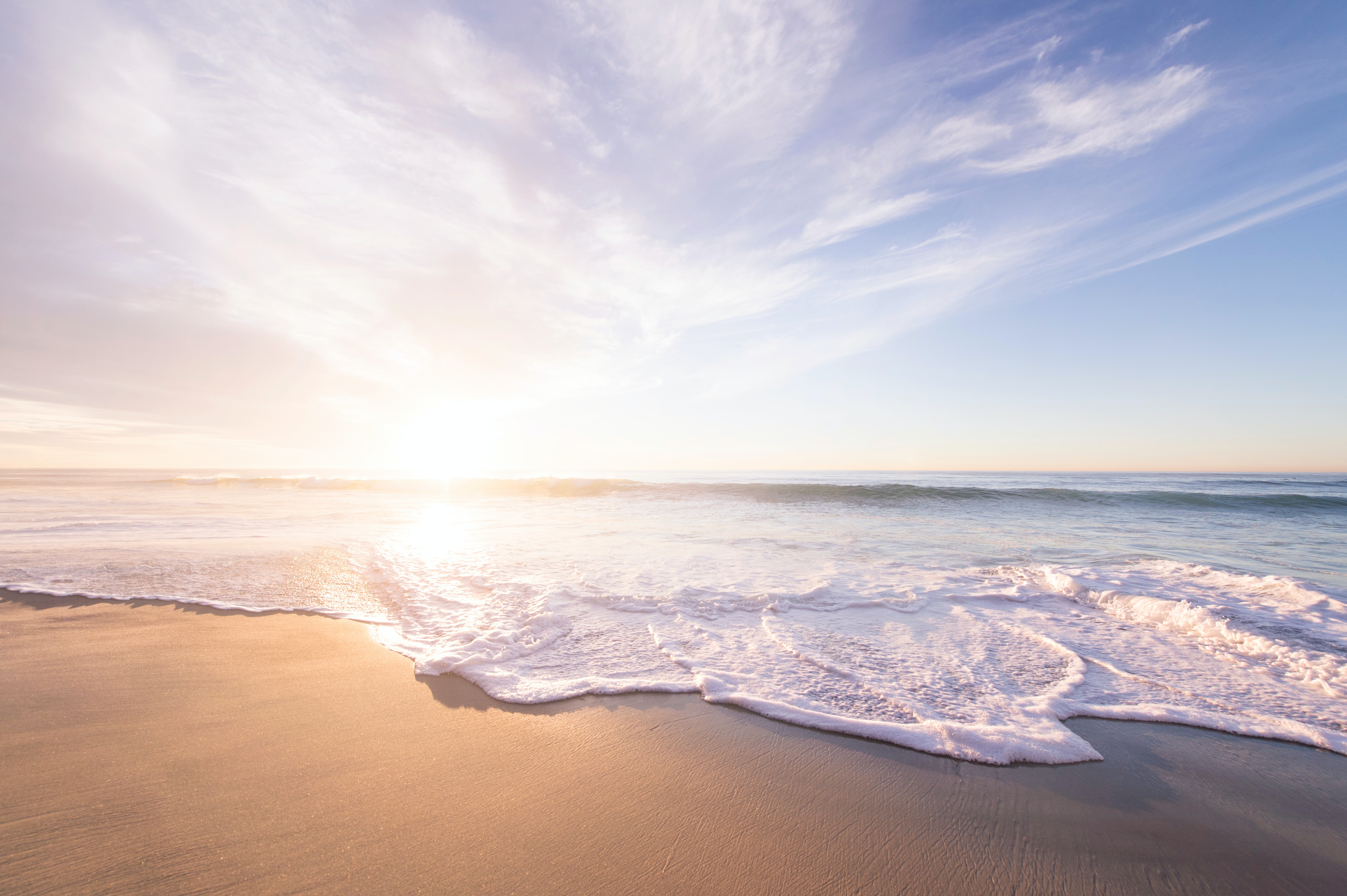 Sunny beach shoreline with gentle waves and bright sky