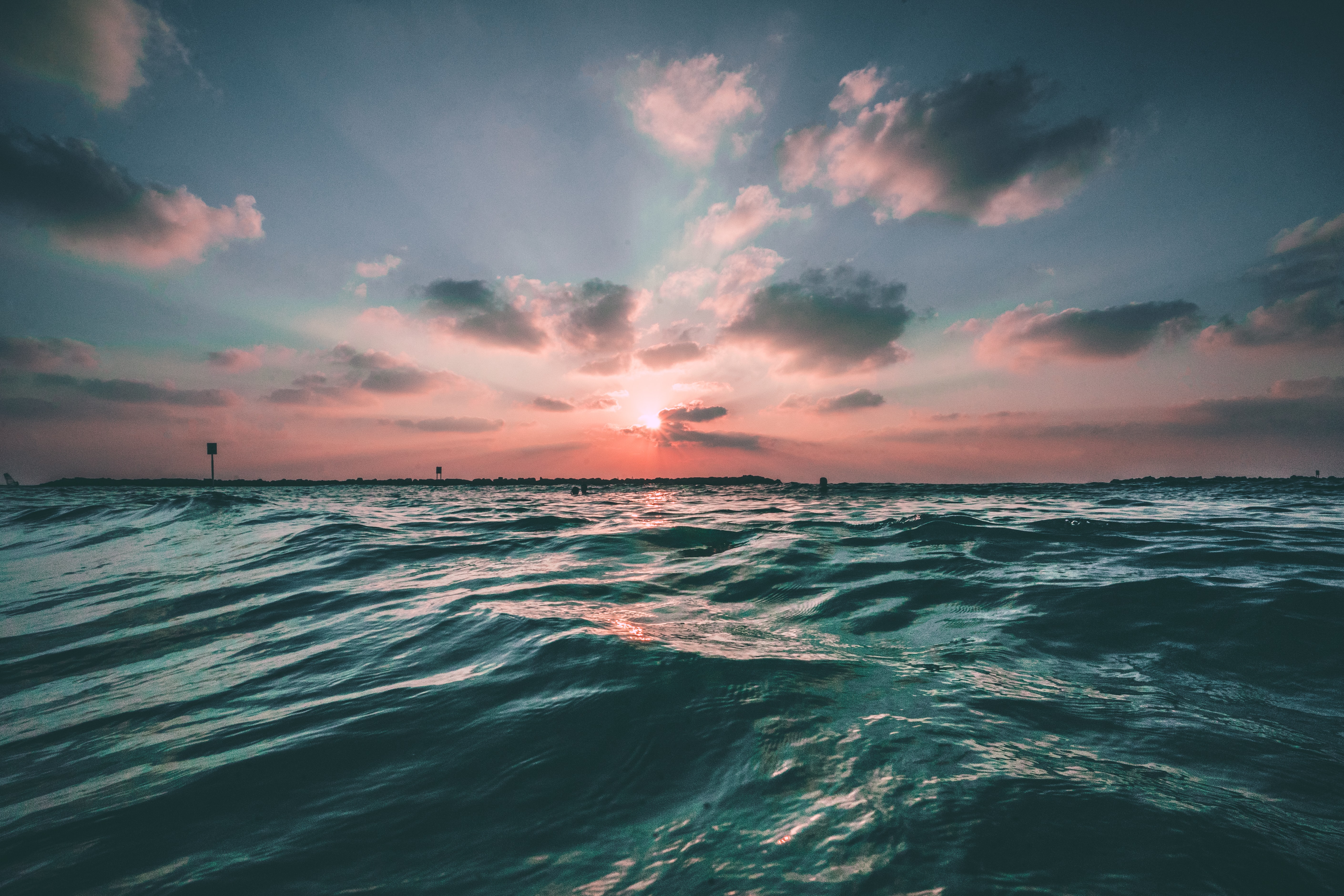Ocean waves at sunset in warm pink and teal tones at low water level