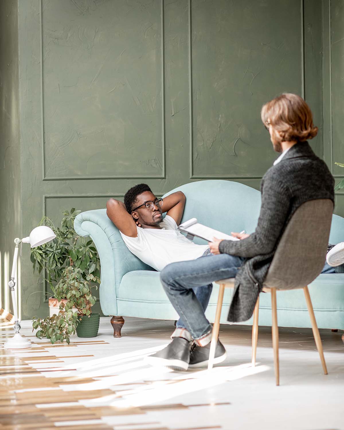 A man in a coaching session with a professional in a warm green-walled office