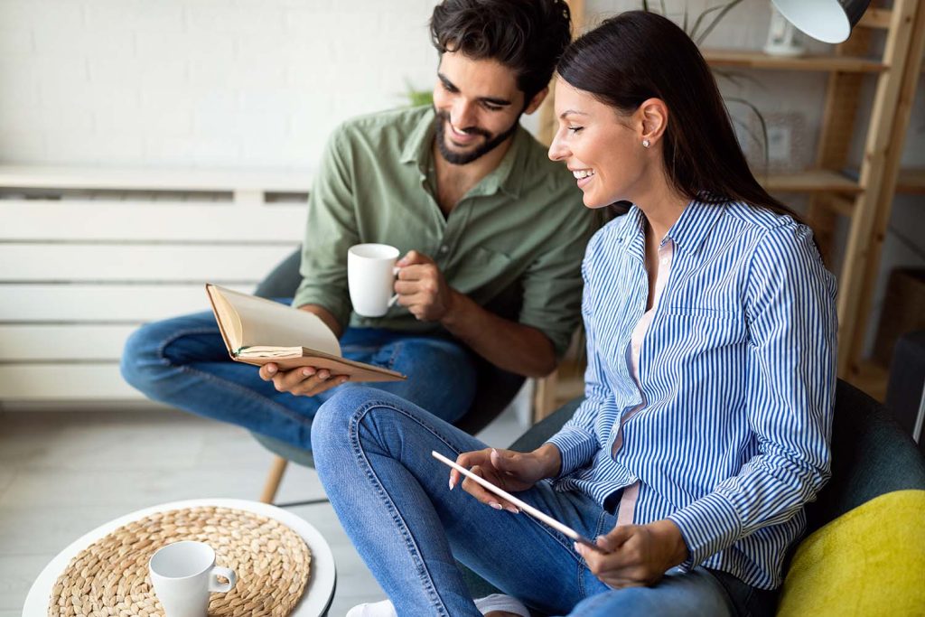 A couple reading a book and using a tablet together
