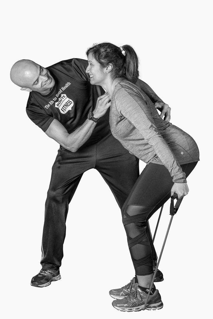 Route Fitness trainer assisting a client with a resistance band exercise