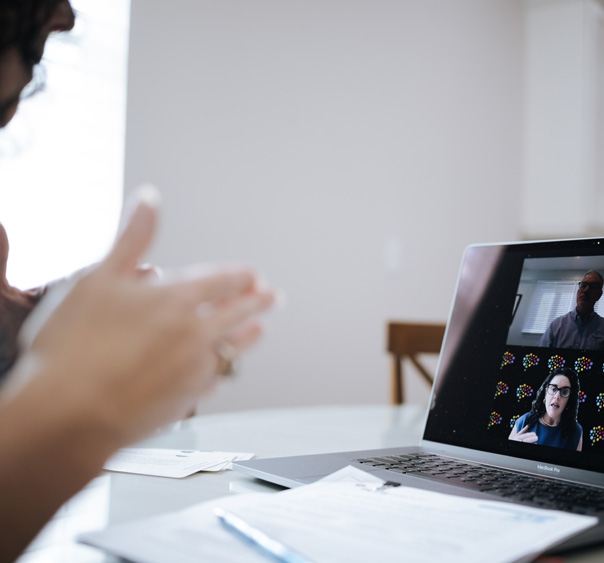 Person gesturing toward a laptop showing a virtual coaching session