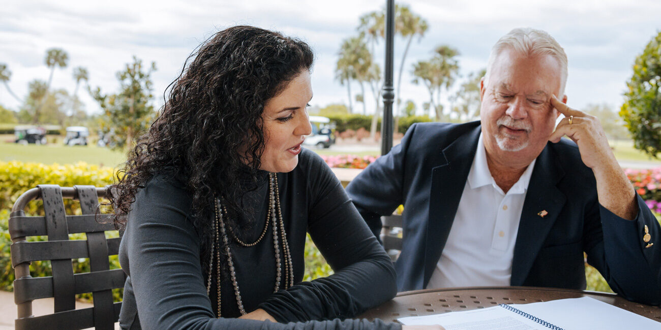 Stacy Berg Jackson consulting an older man outdoors at a golf-course setting