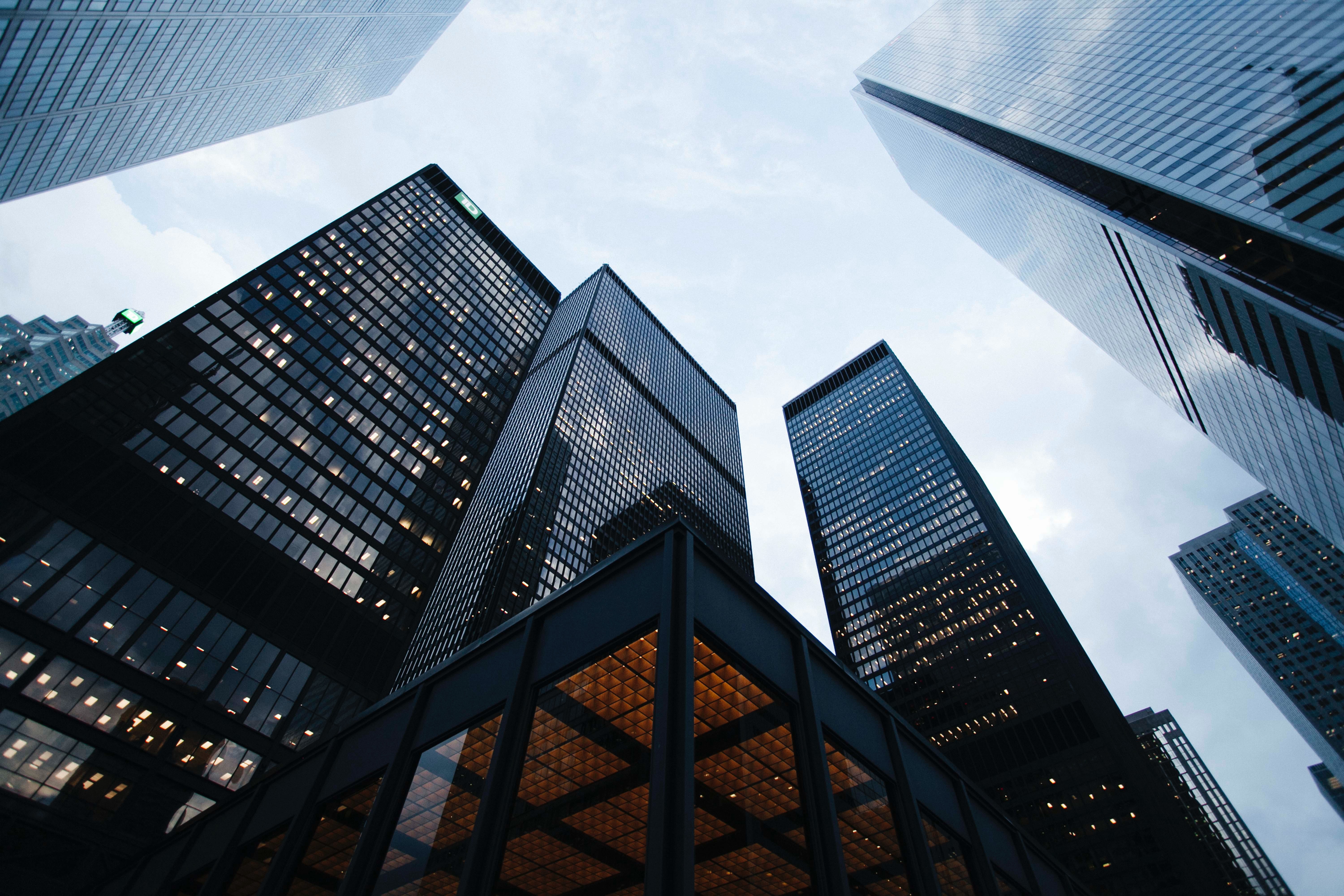 Upward view of tall glass office towers against a cloudy sky