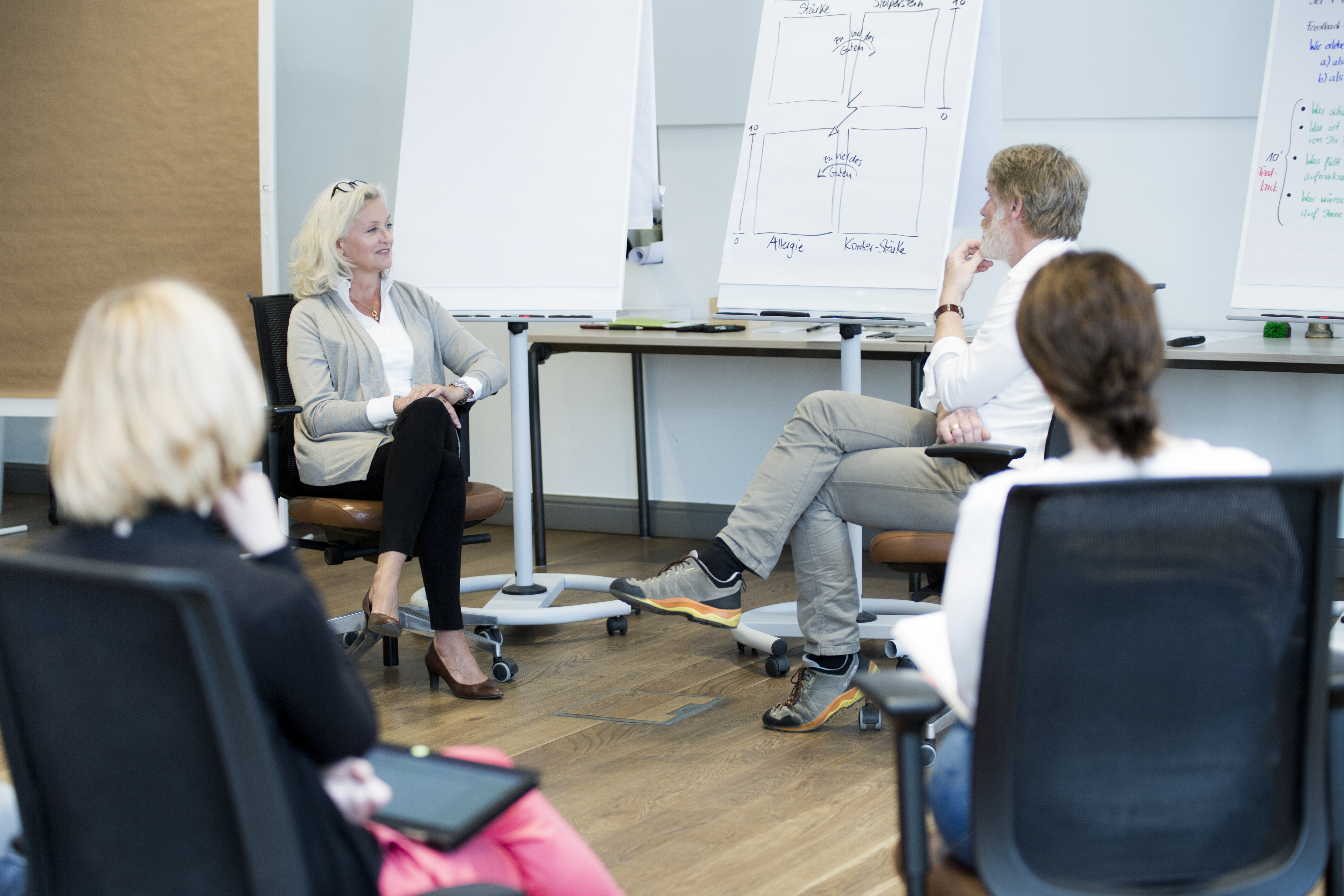 Leaders in a Second Freedom coaching workshop, seated in a circle with whiteboards behind them.