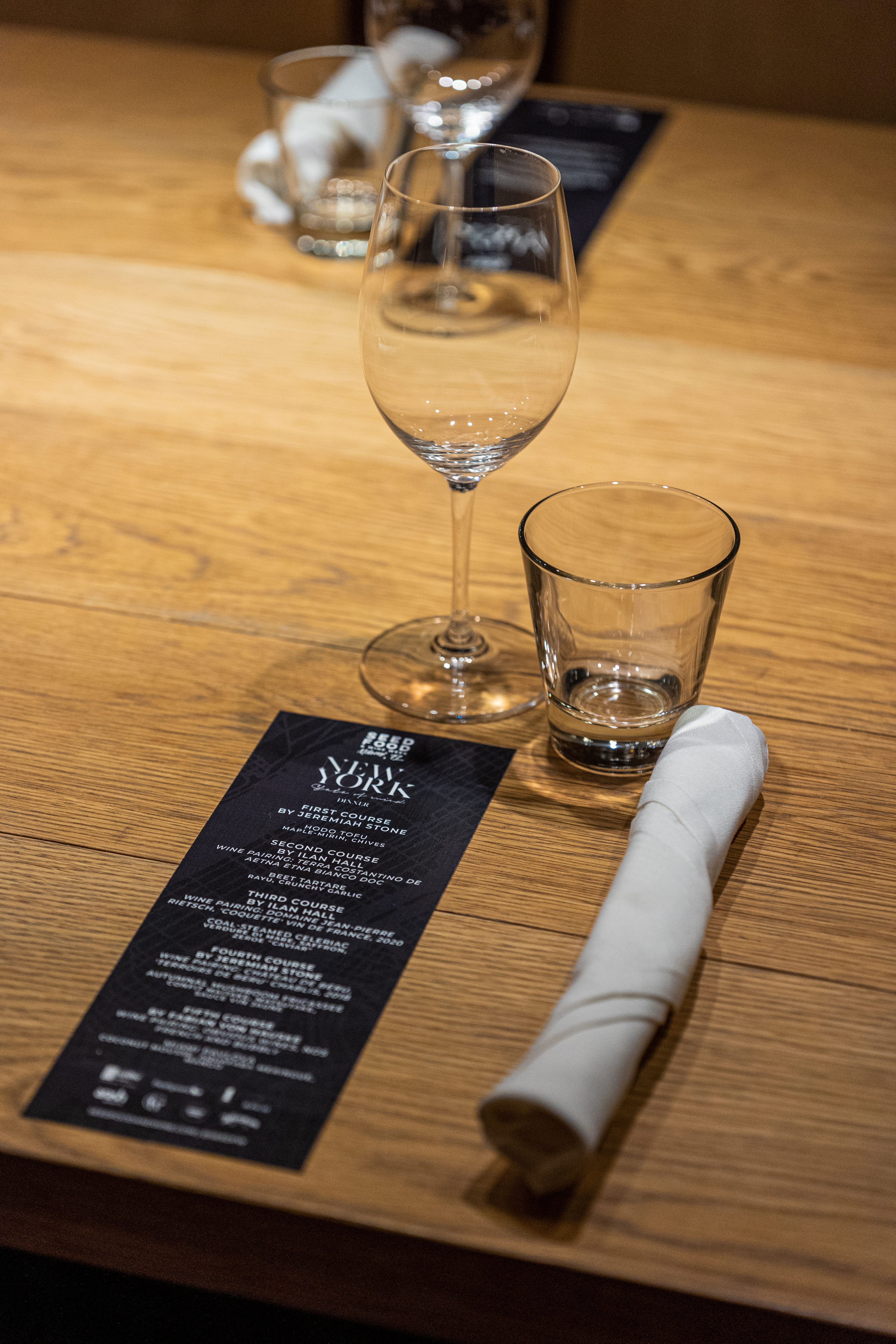 Dinner table set with wine glasses and a Seed Food & Wine Week menu card