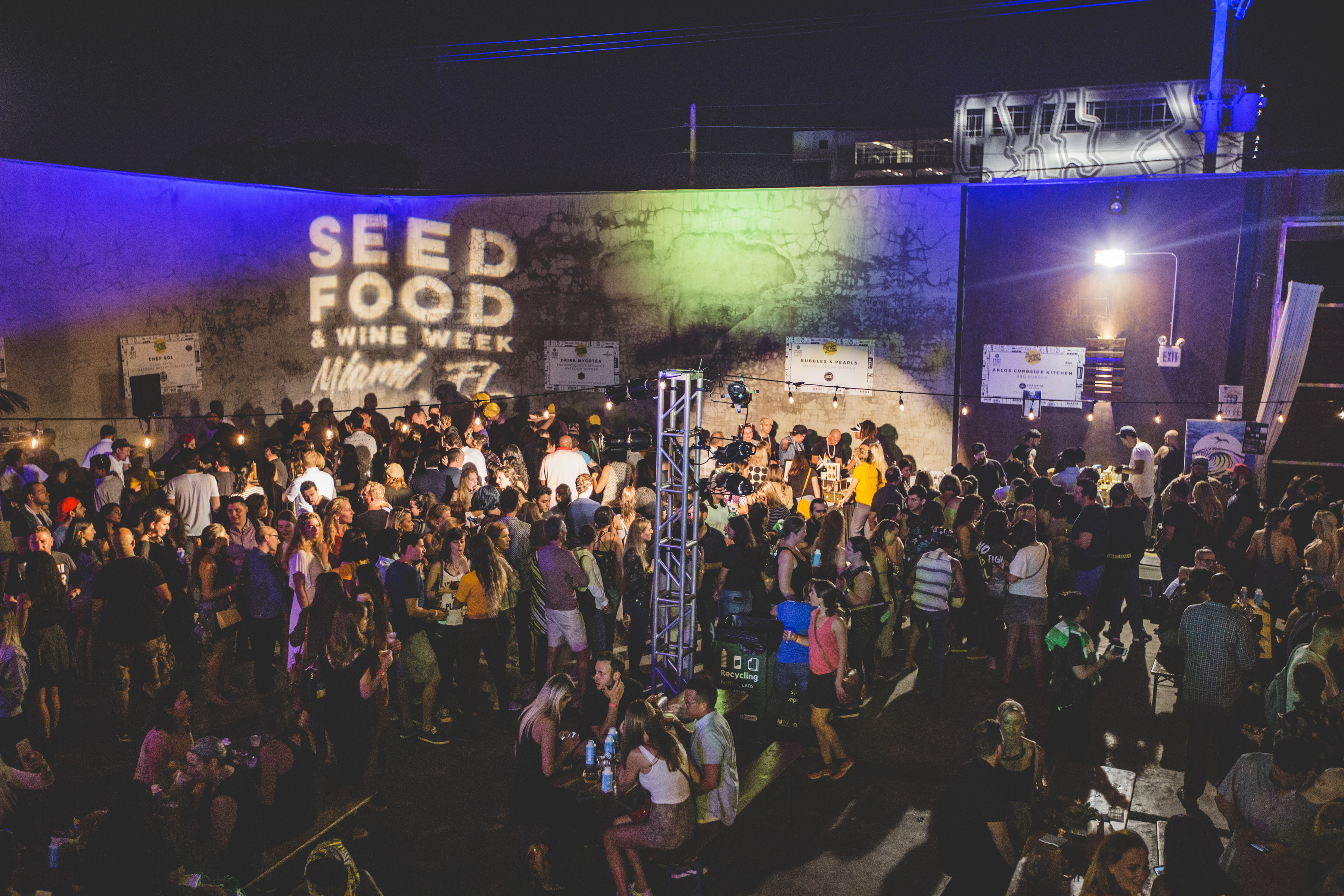 Huge nighttime festival crowd with Seed Food & Wine Week Miami projected on a wall