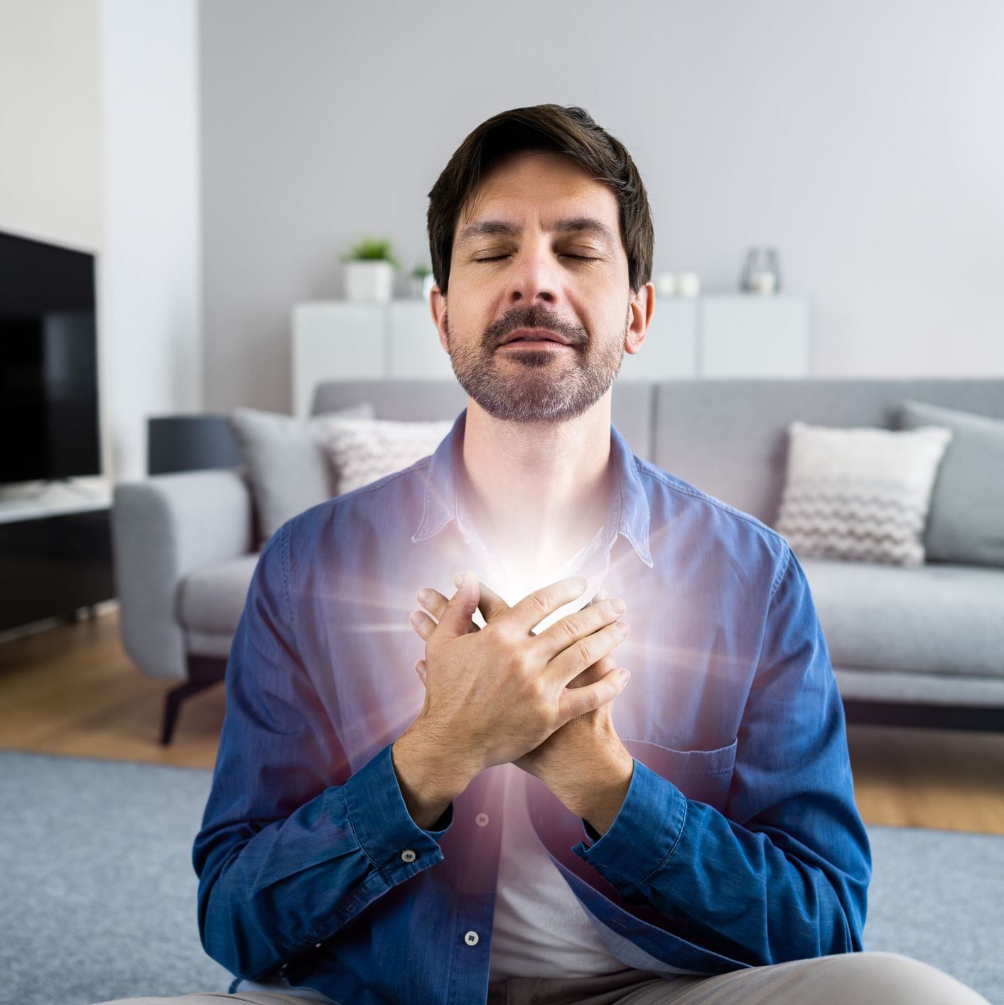 Man meditating with glowing light energy emanating from his clasped hands