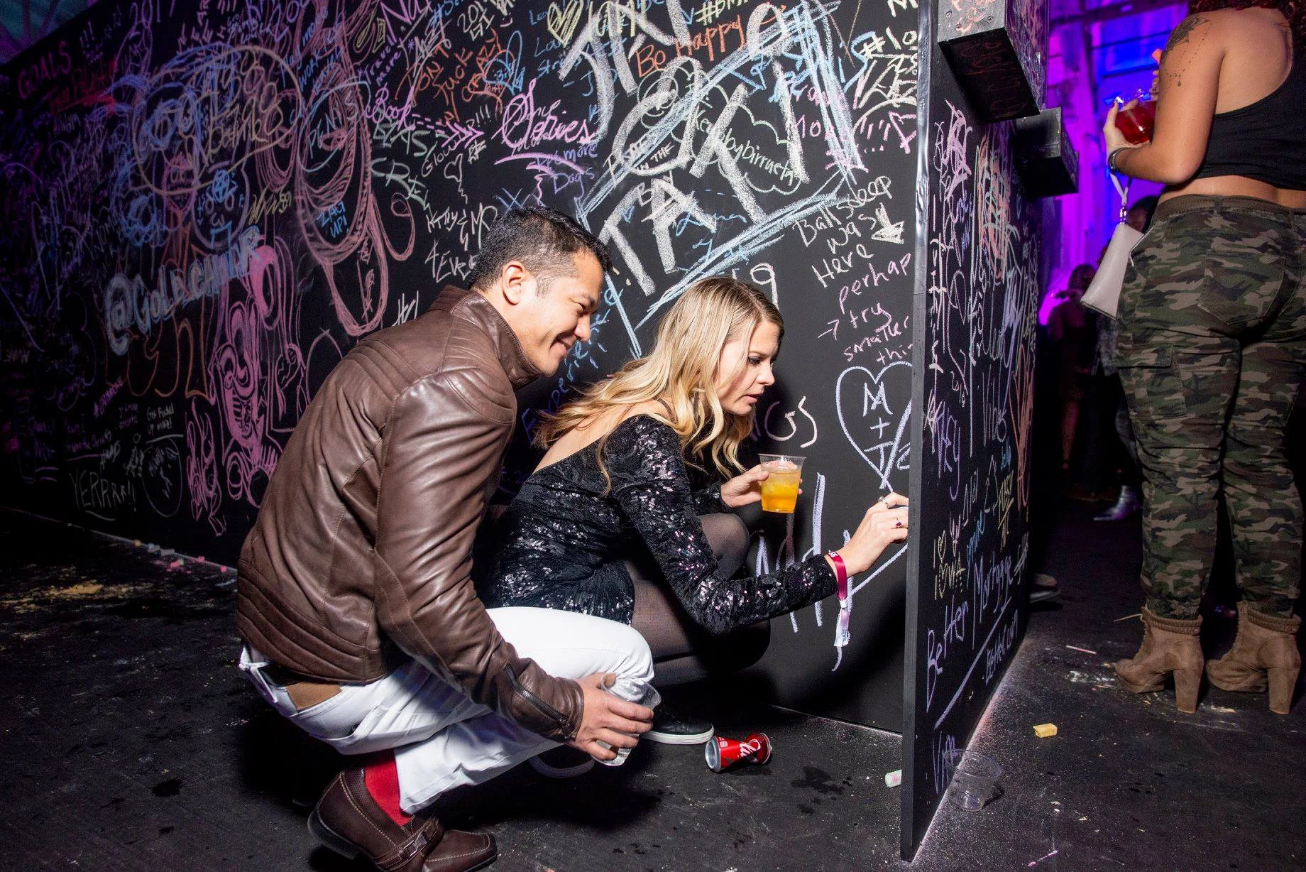 Guests writing on a graffiti chalkboard wall