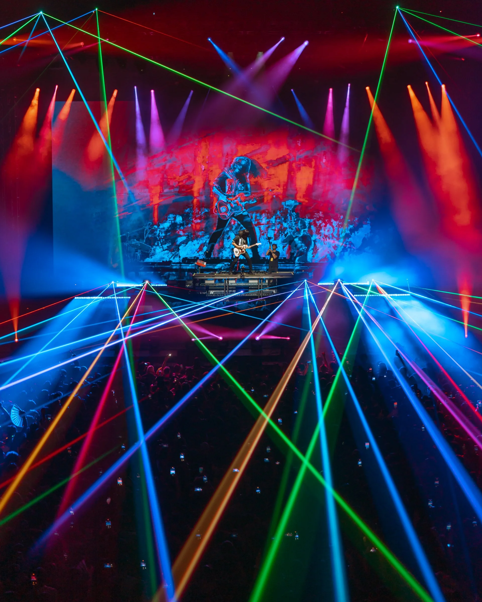 Gryffin performing on stage with a full laser light show above a huge crowd