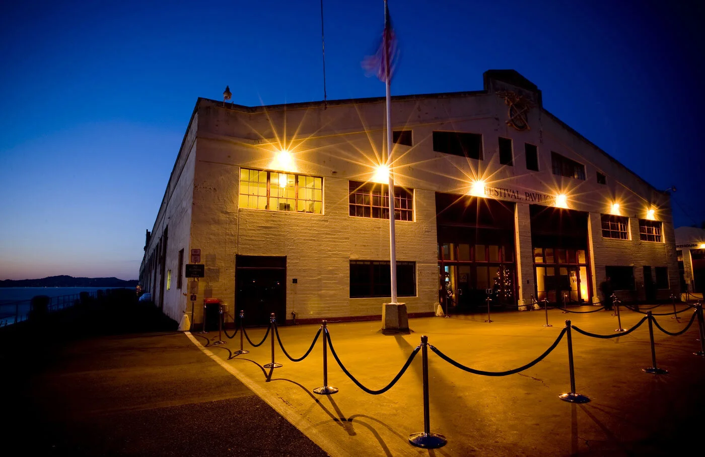 Fort Mason Center Festival Pavilion at twilight with velvet ropes and a flag