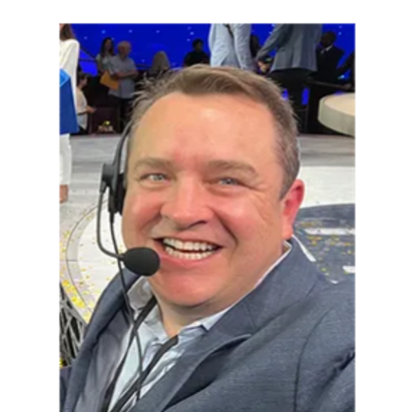 Gregory C. Schaefer smiling in a headset on site at a live event