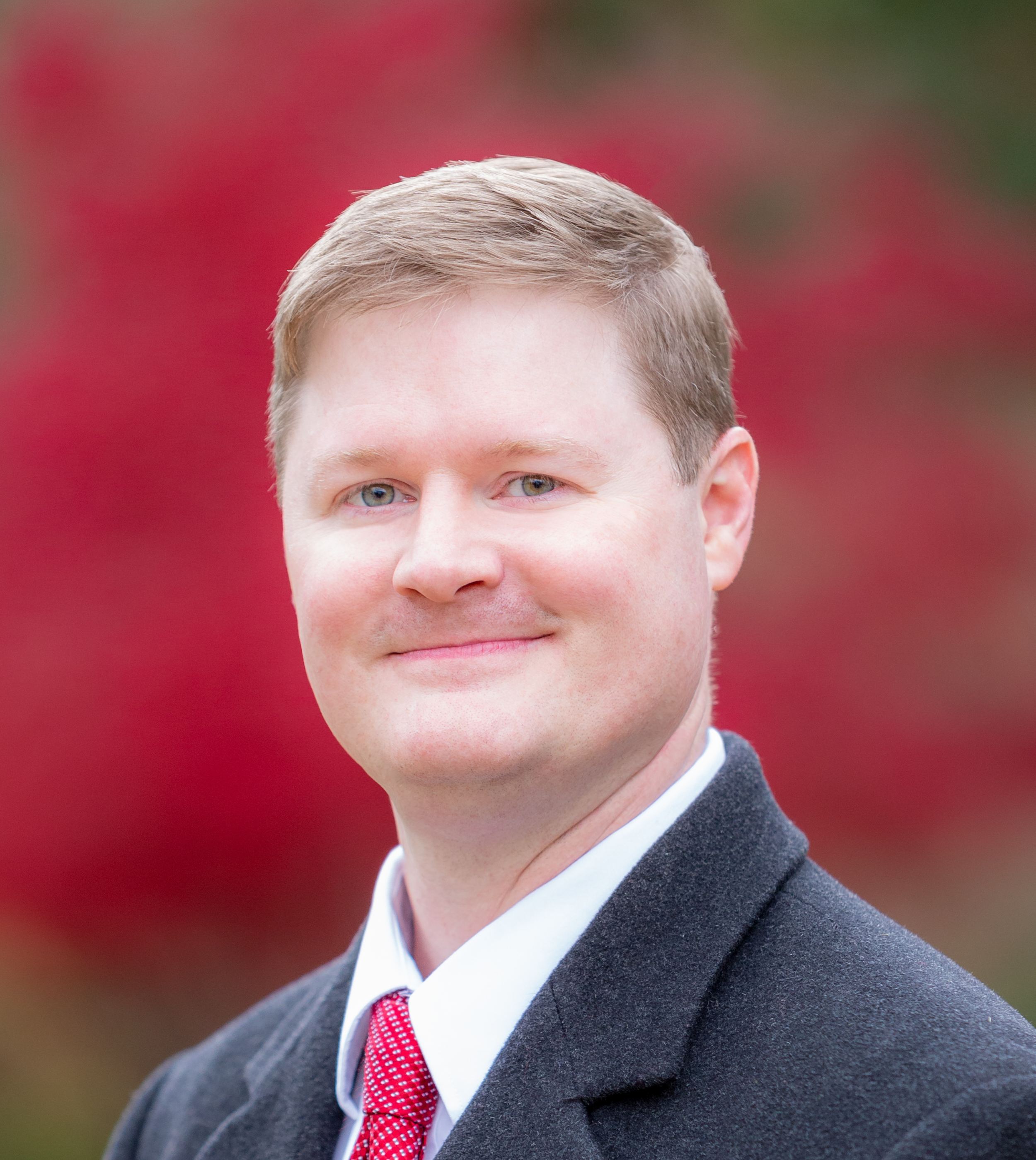 Michael Luthi, in a grey blazer and red tie, professional headshot
