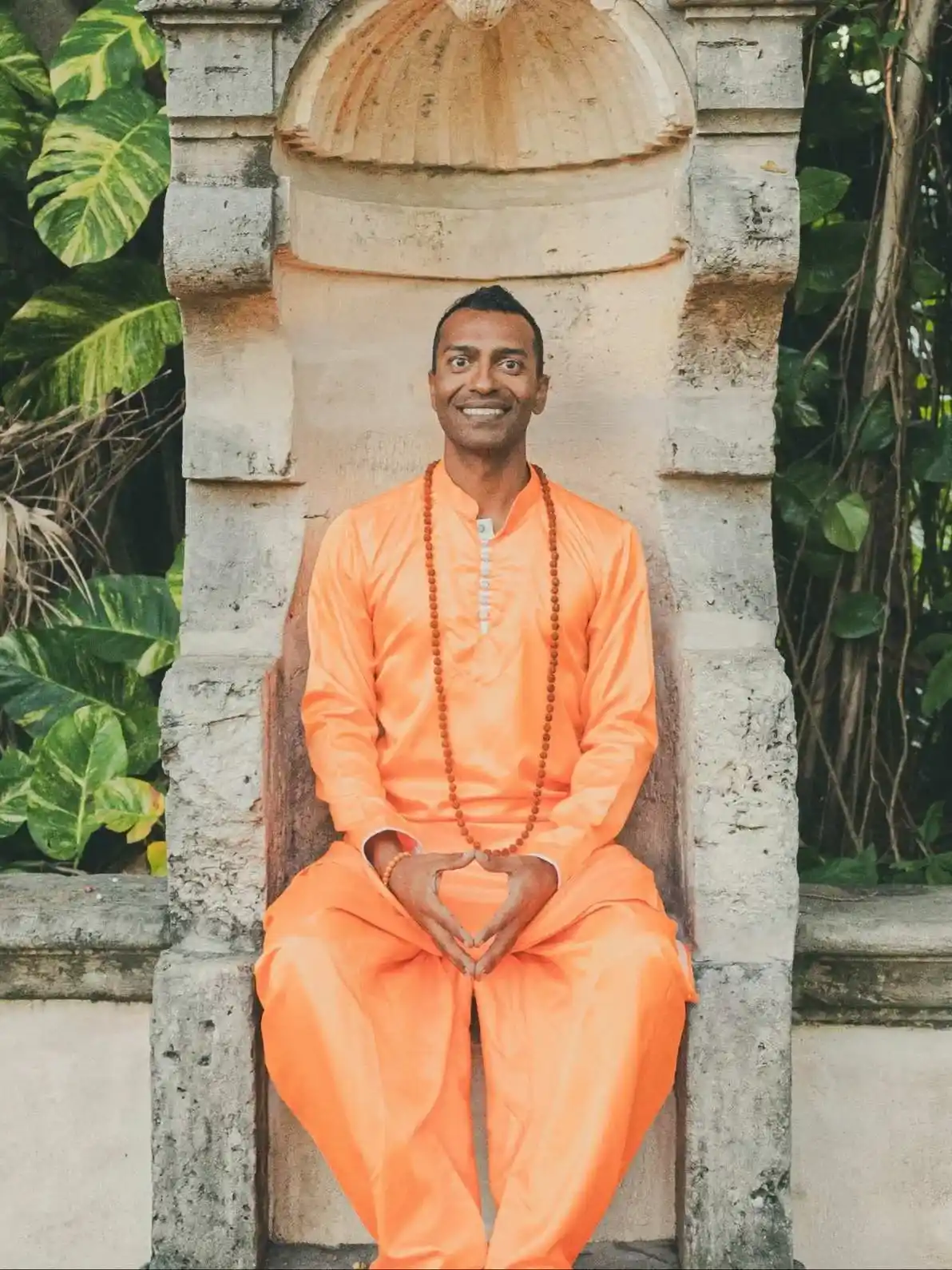 Sri Sudarshan seated among tropical plants