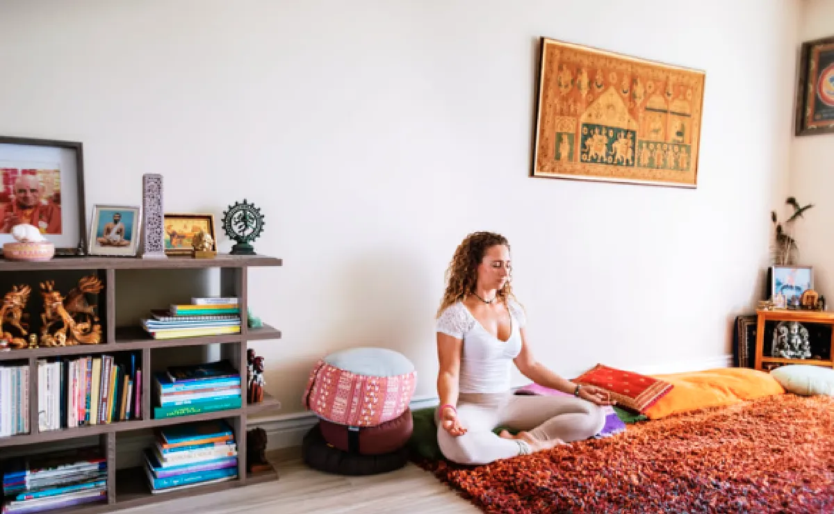 Woman meditating in a yoga room with statues and bookshelves