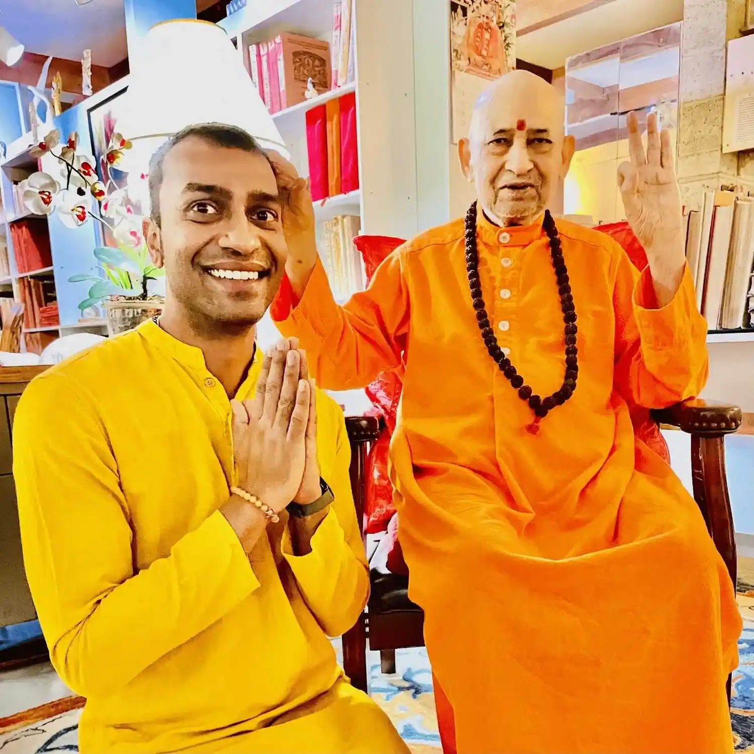 Sri Sudarshan in a yellow kurta beside his guru in a library