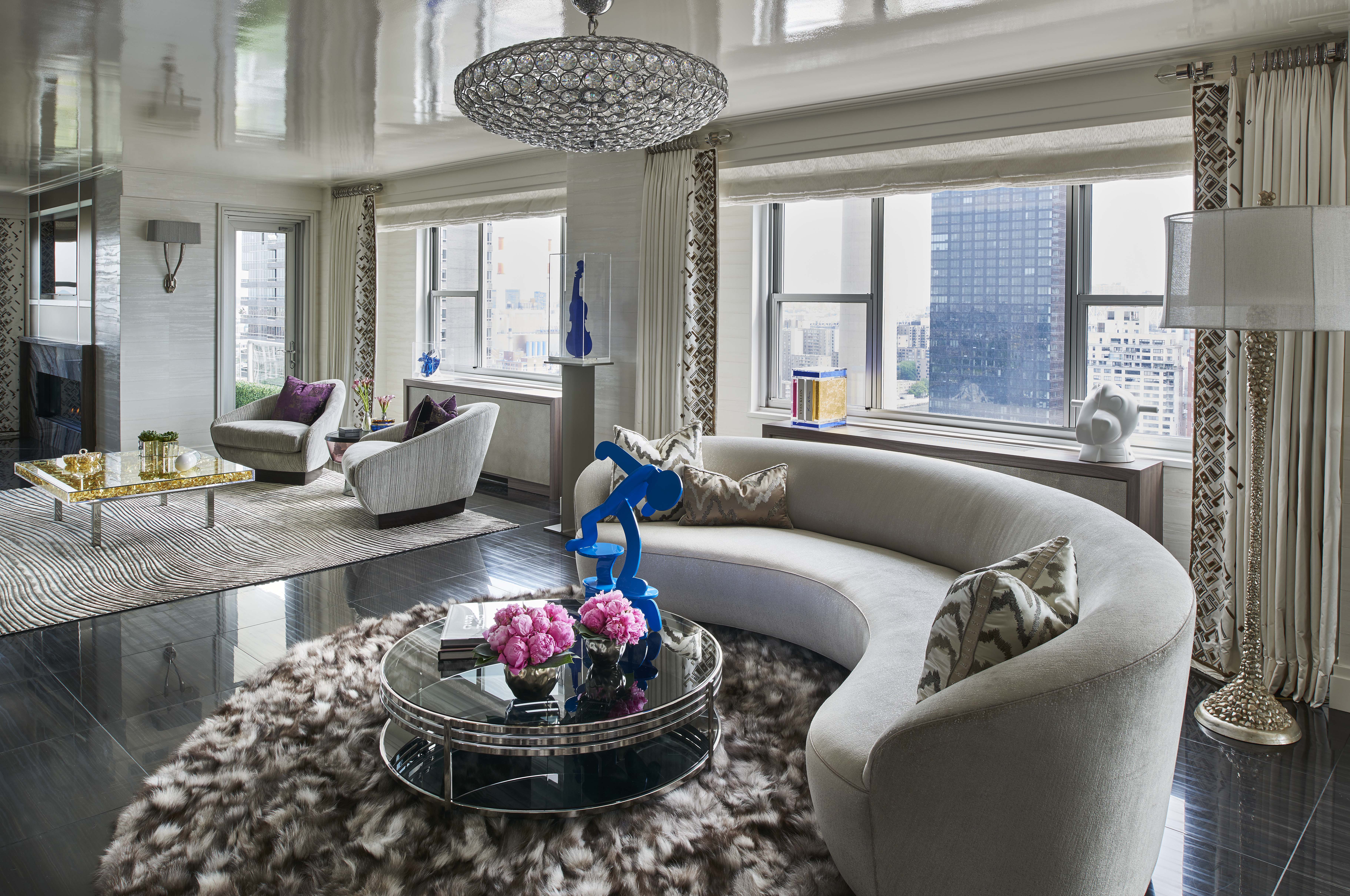 Luxurious high-rise living room with curved sectional sofa, fur rug, blue sculptural accents and city skyline views