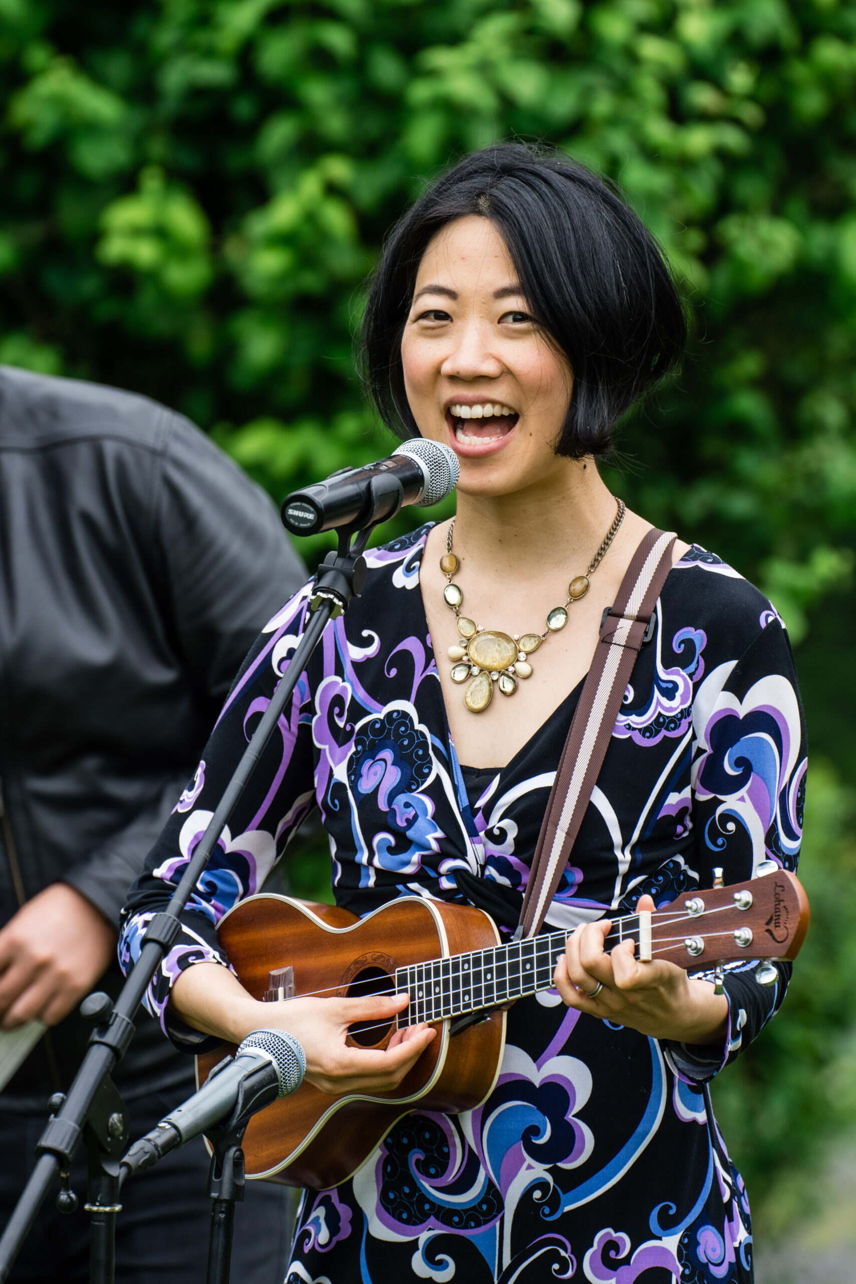 Anna Choi singing and playing ukulele at an outdoor performance