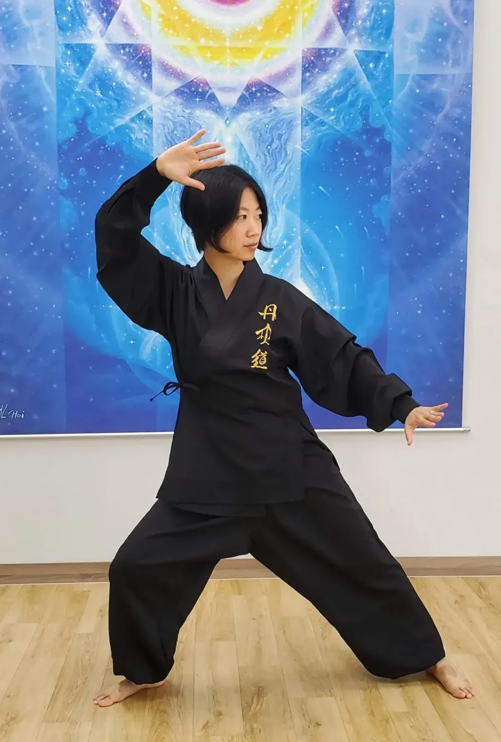 Anna Choi performing a qigong stance in front of a cosmic mural