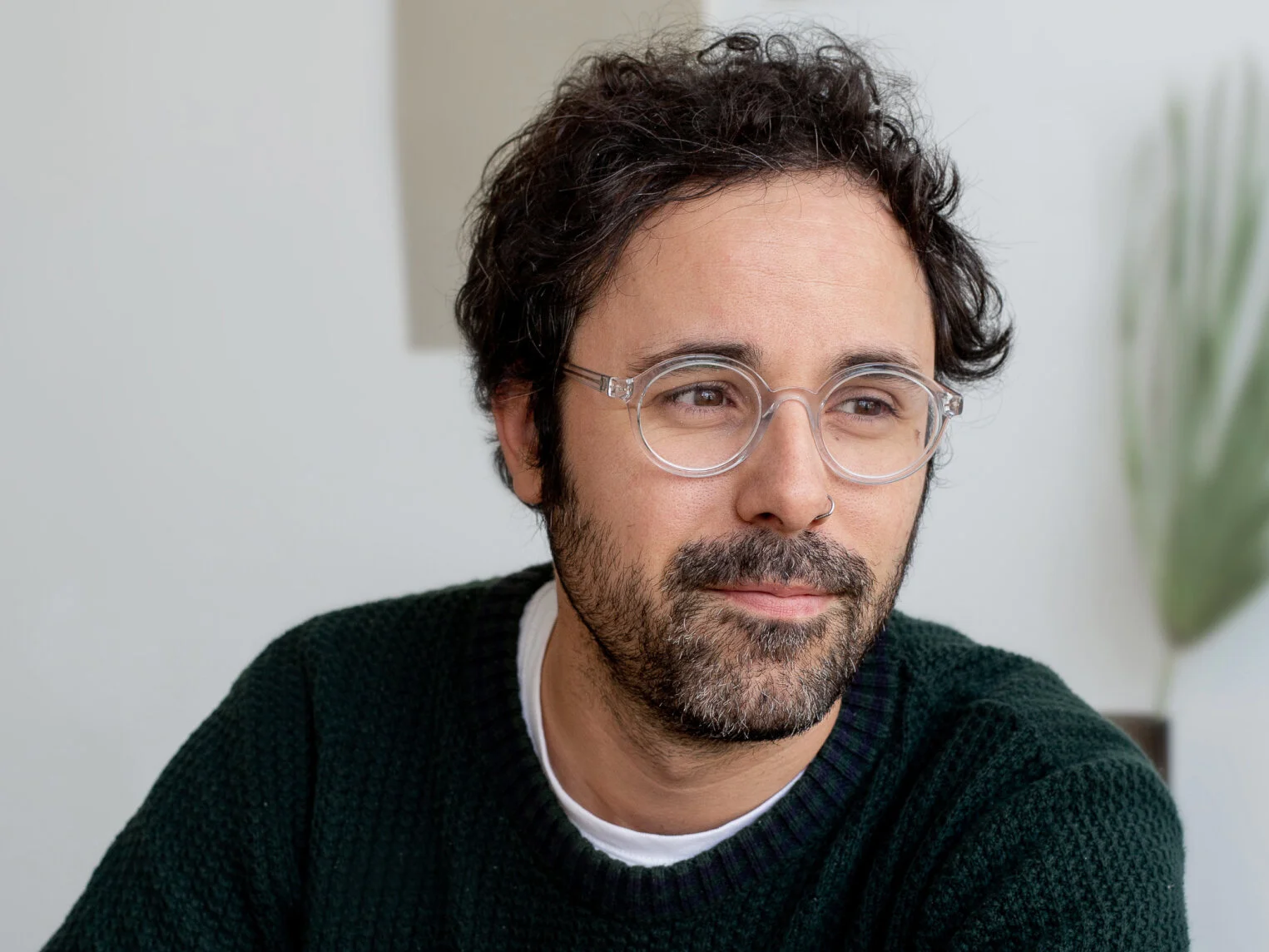 Portrait of Steven Chandler, a man with dark curly hair, a beard and round clear glasses in a dark green sweater