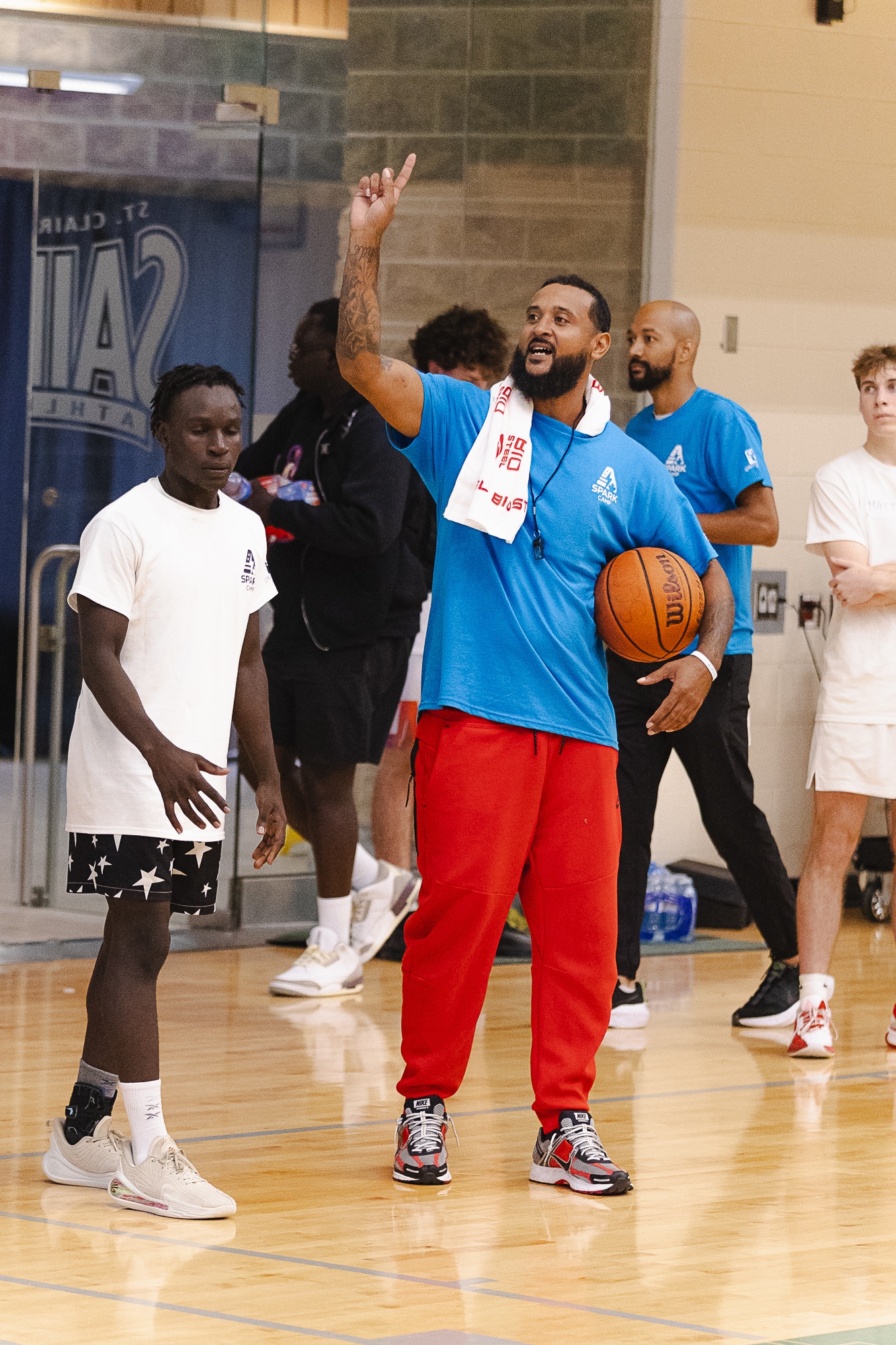 Coach holding a basketball and pointing upward