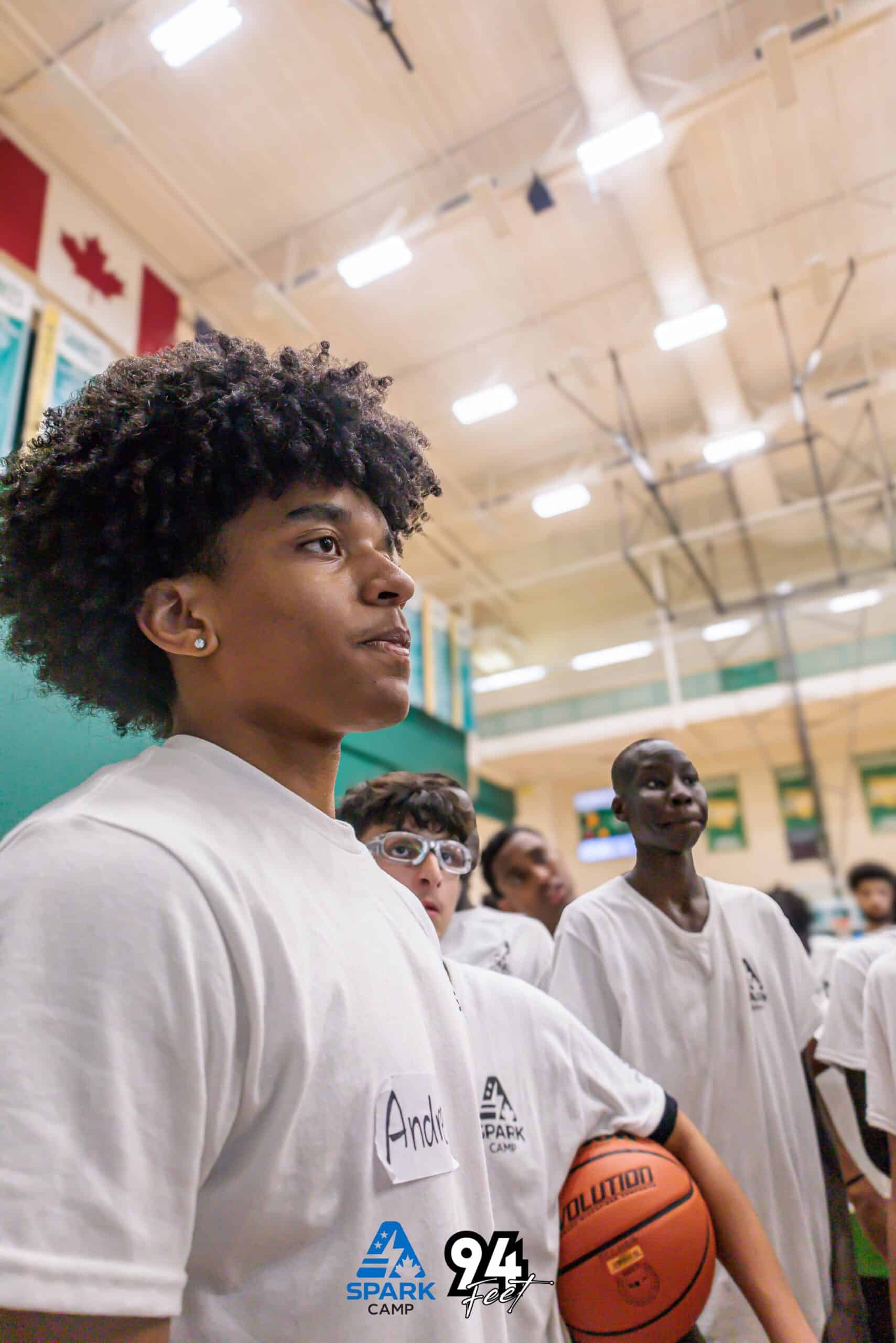 Teen camper holding a basketball and looking up