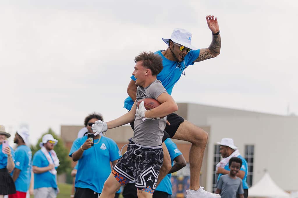 Coach celebrating with a camper during an outdoor football session