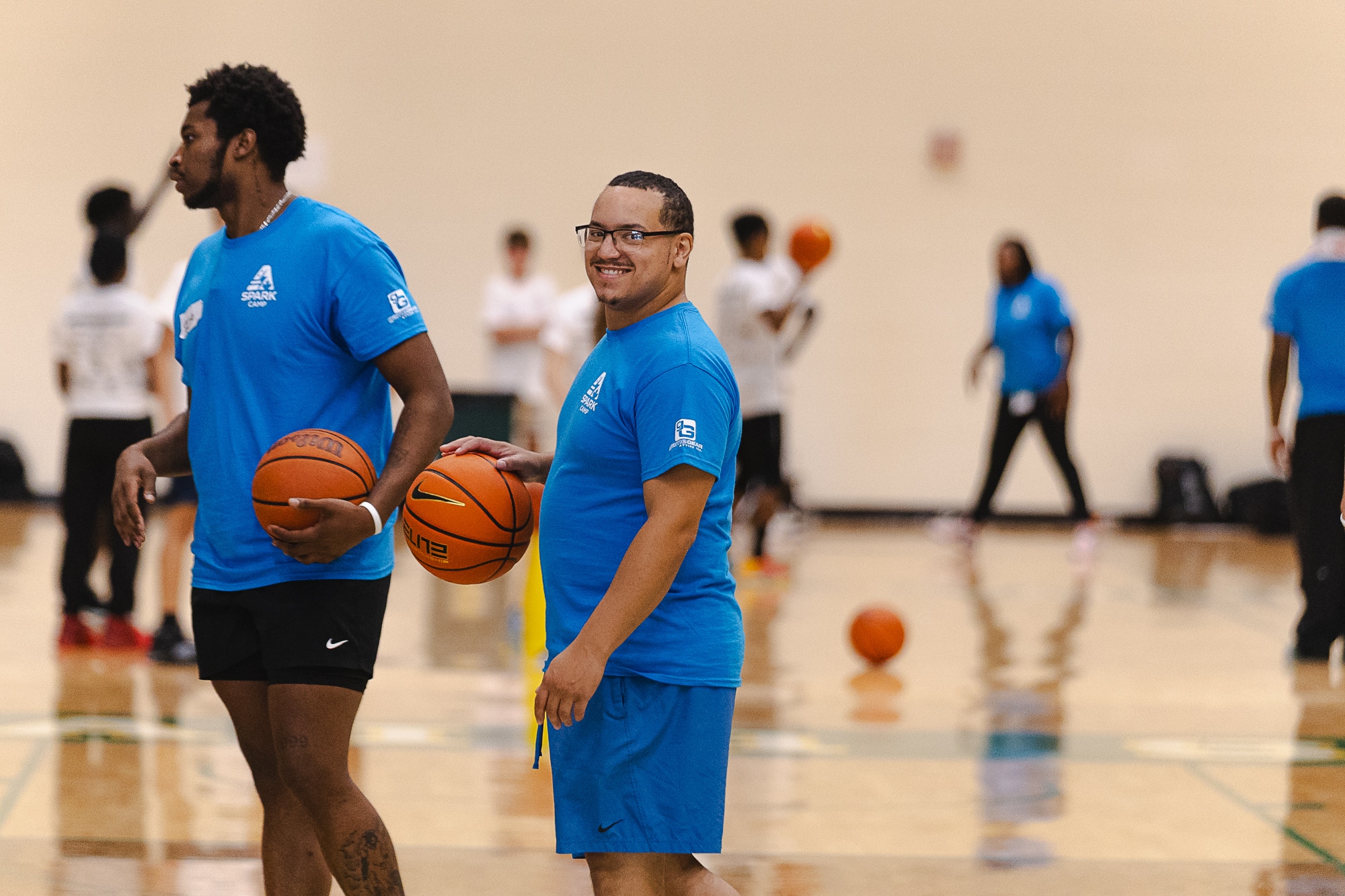 Two Spark Camp coaches holding basketballs on court