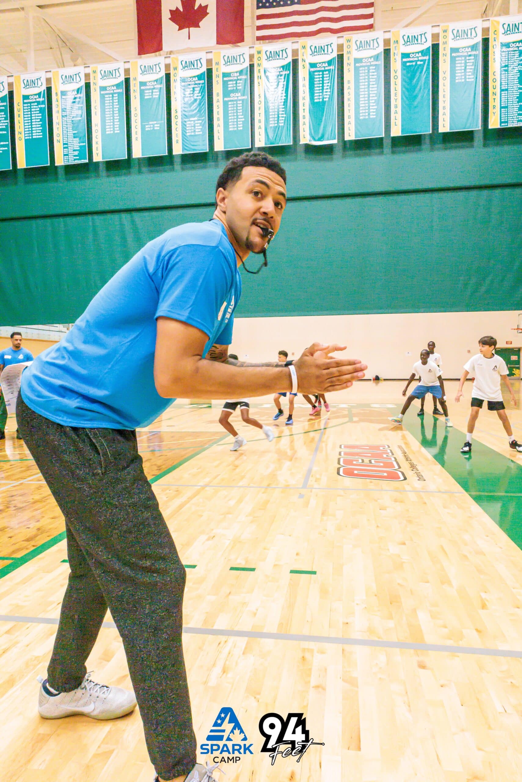 Coach directing players in a gym with championship banners