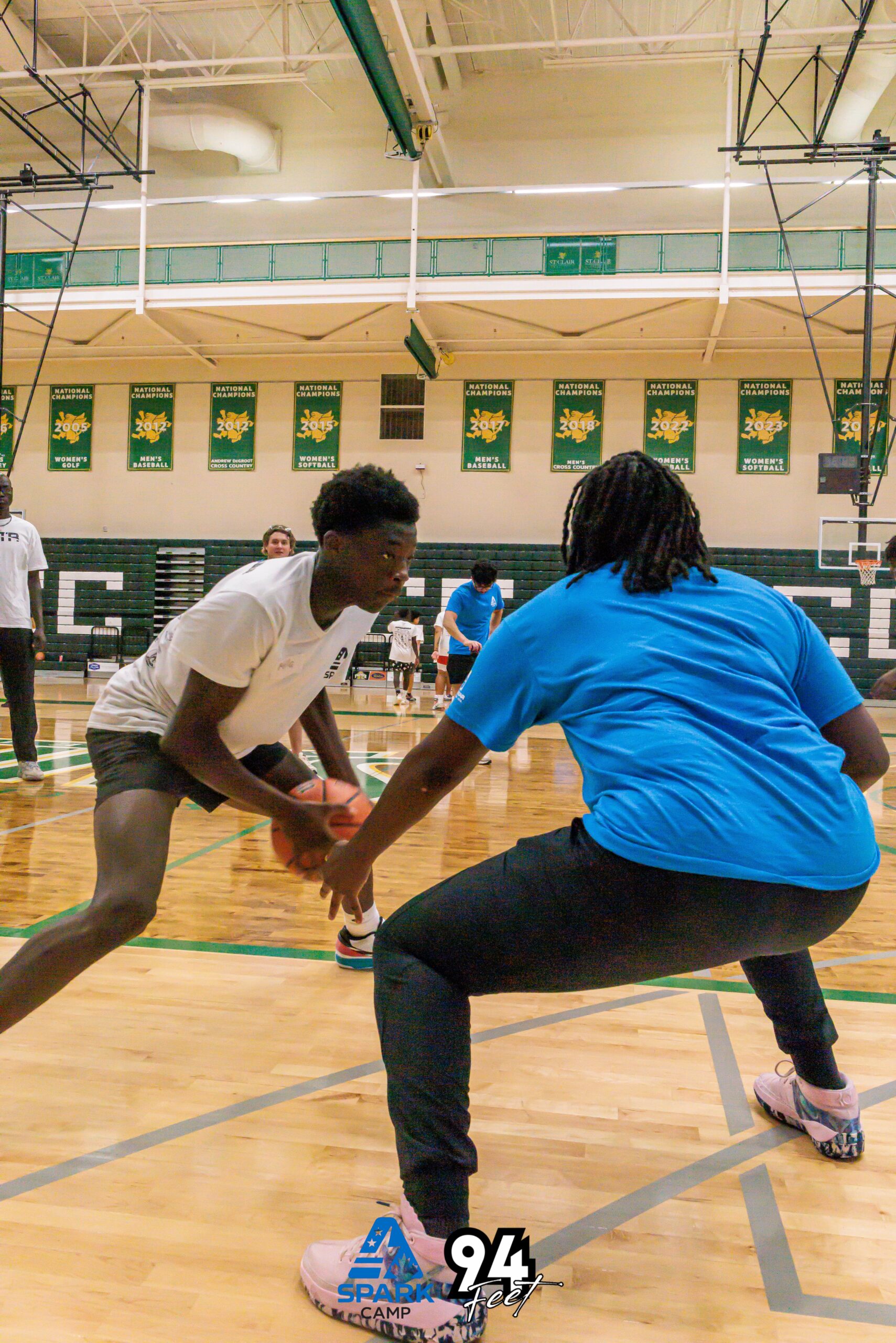 Two players practicing one-on-one basketball defense in a gym