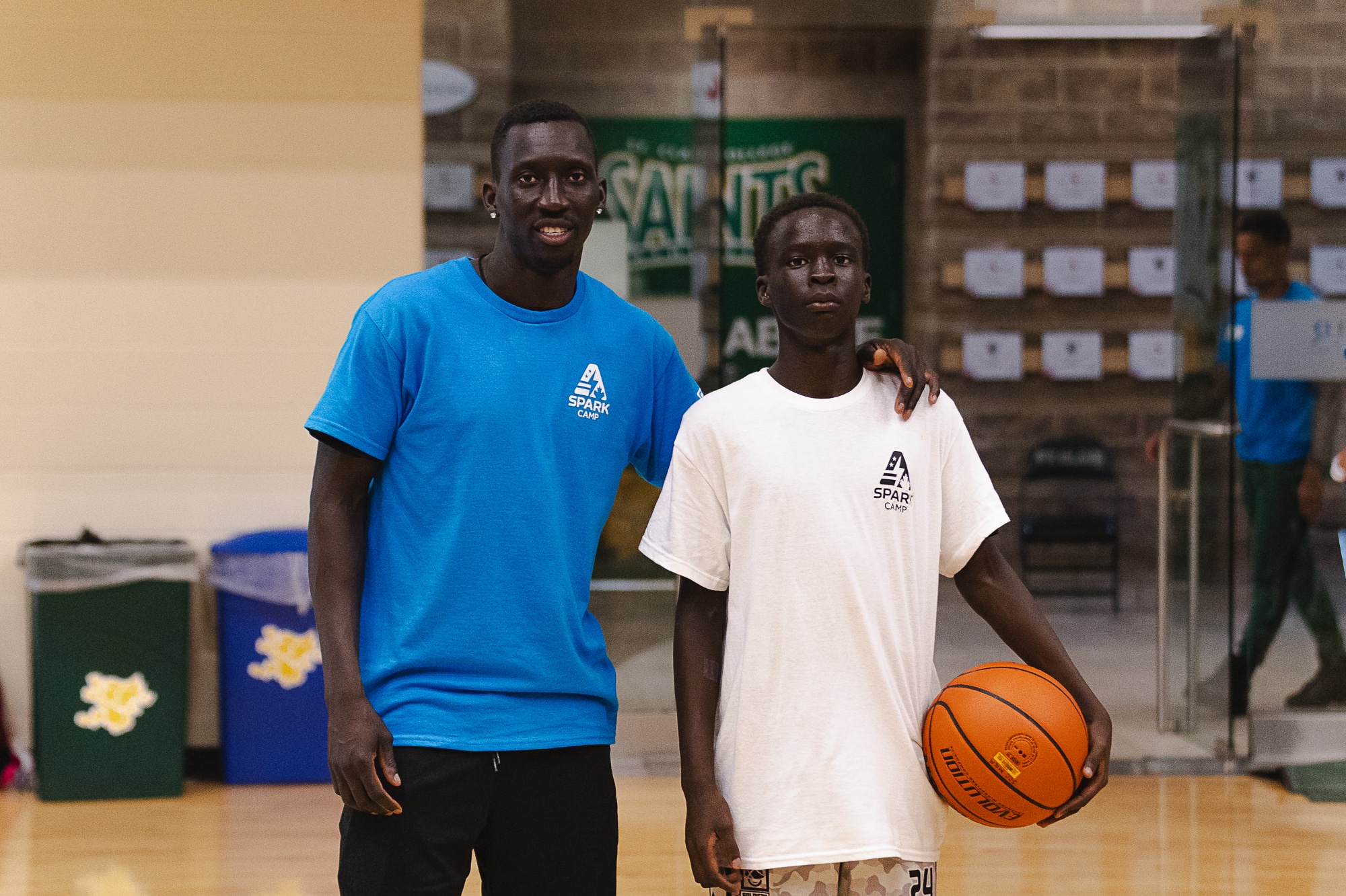 Spark Camp coach posing with a young camper holding a basketball