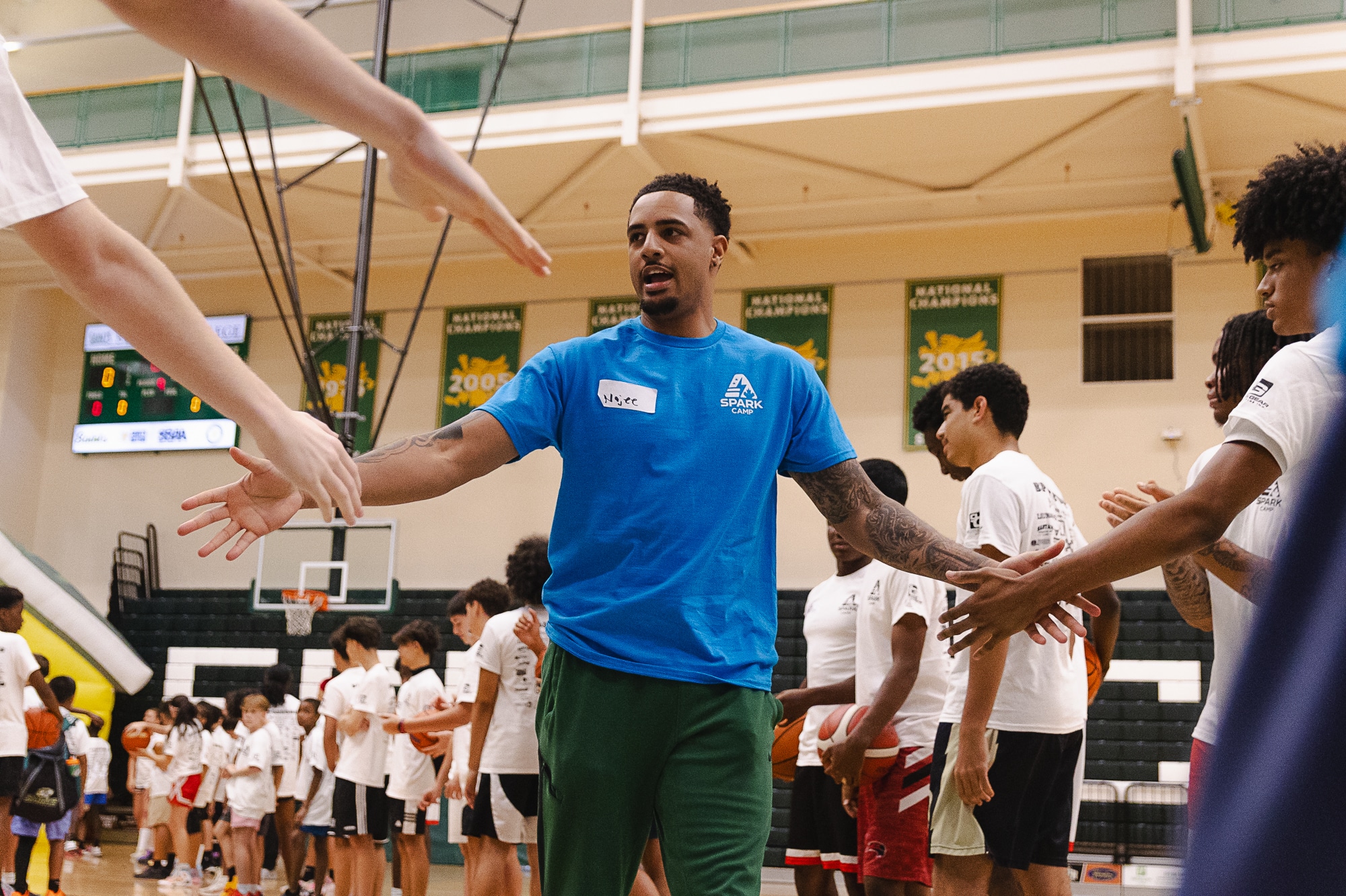 Spark Camp coach high-fiving a line of campers on court