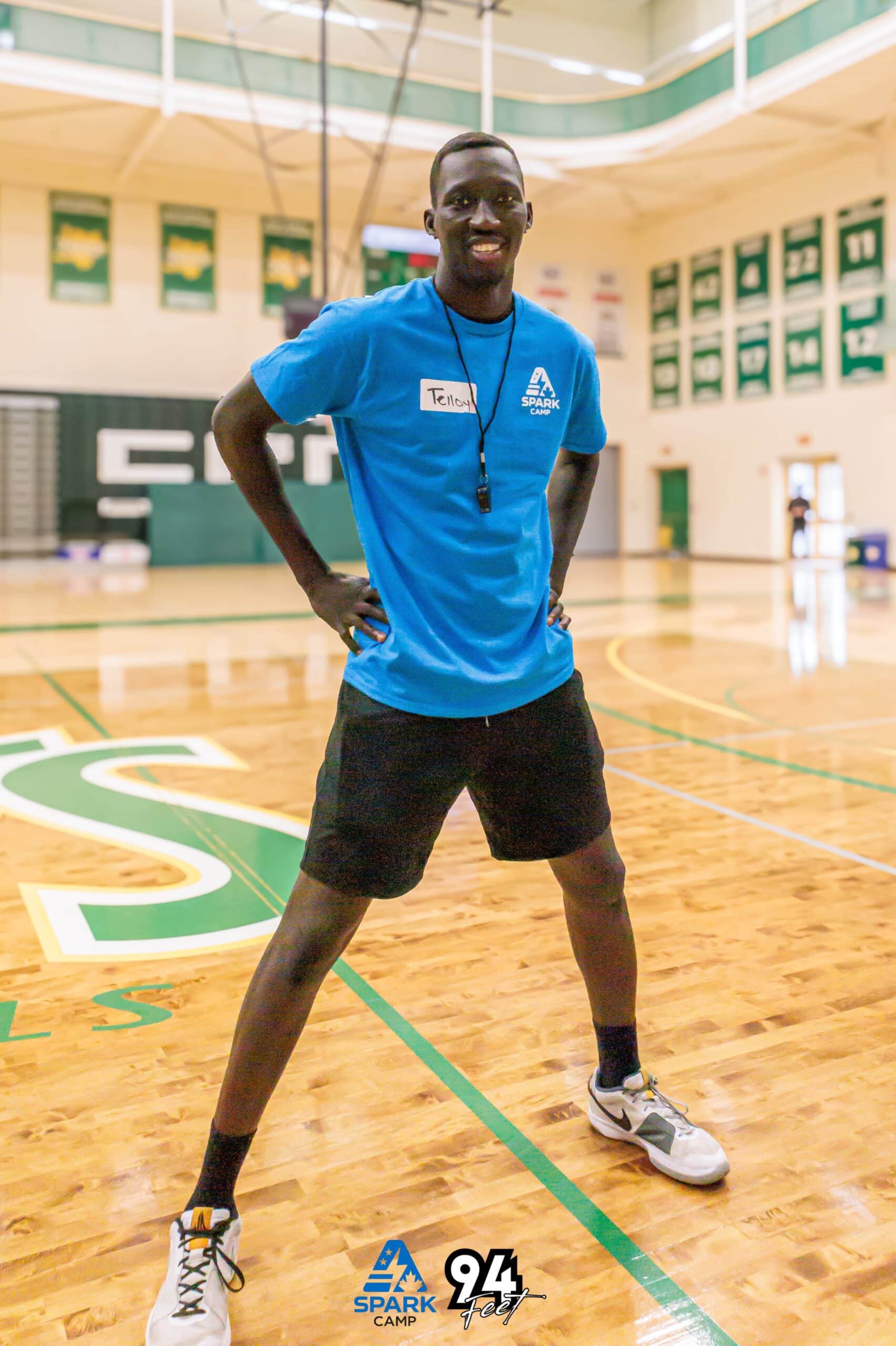 Young athlete in a blue Spark Camp shirt posing on the court