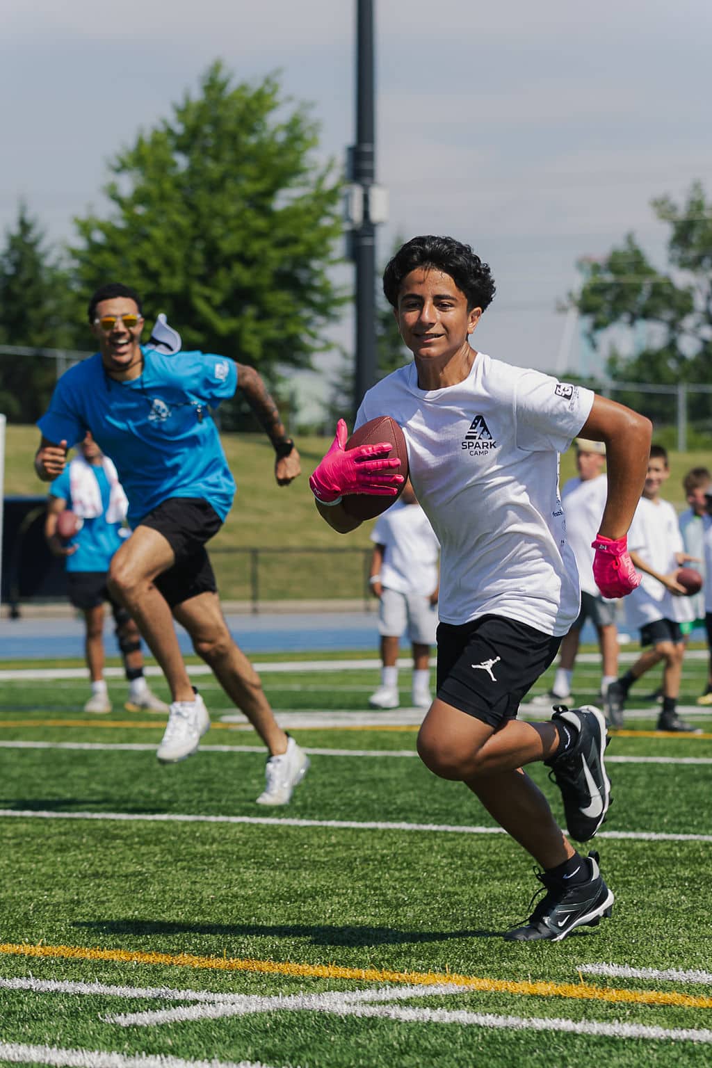 Camper running with a football while a coach chases behind