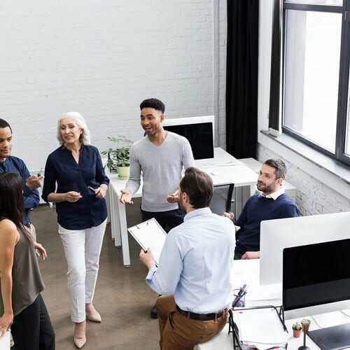 Six diverse professionals conversing in a bright modern office