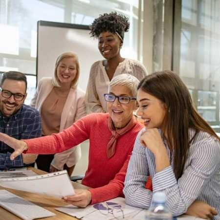 Five diverse professionals at a conference table reviewing a document together