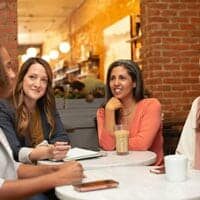 Four women laughing and conversing at a table