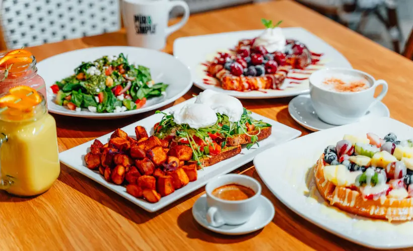 Dining Guide — overhead brunch spread with avocado toast, waffles, salad, smoothie and coffee